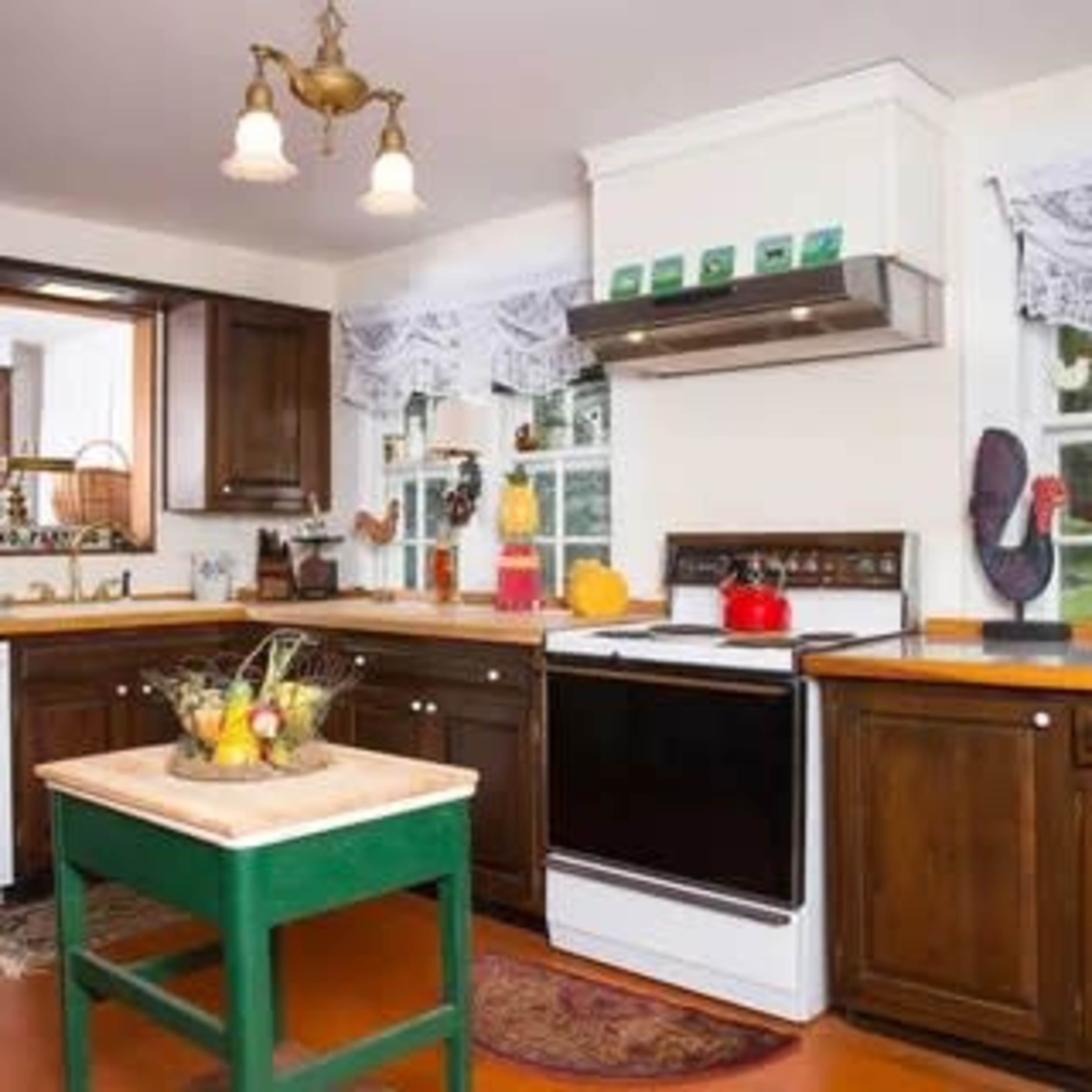 A spacious kitchen features dark wooden cabinets, a central green island, and a white stove with a stainless steel hood.
