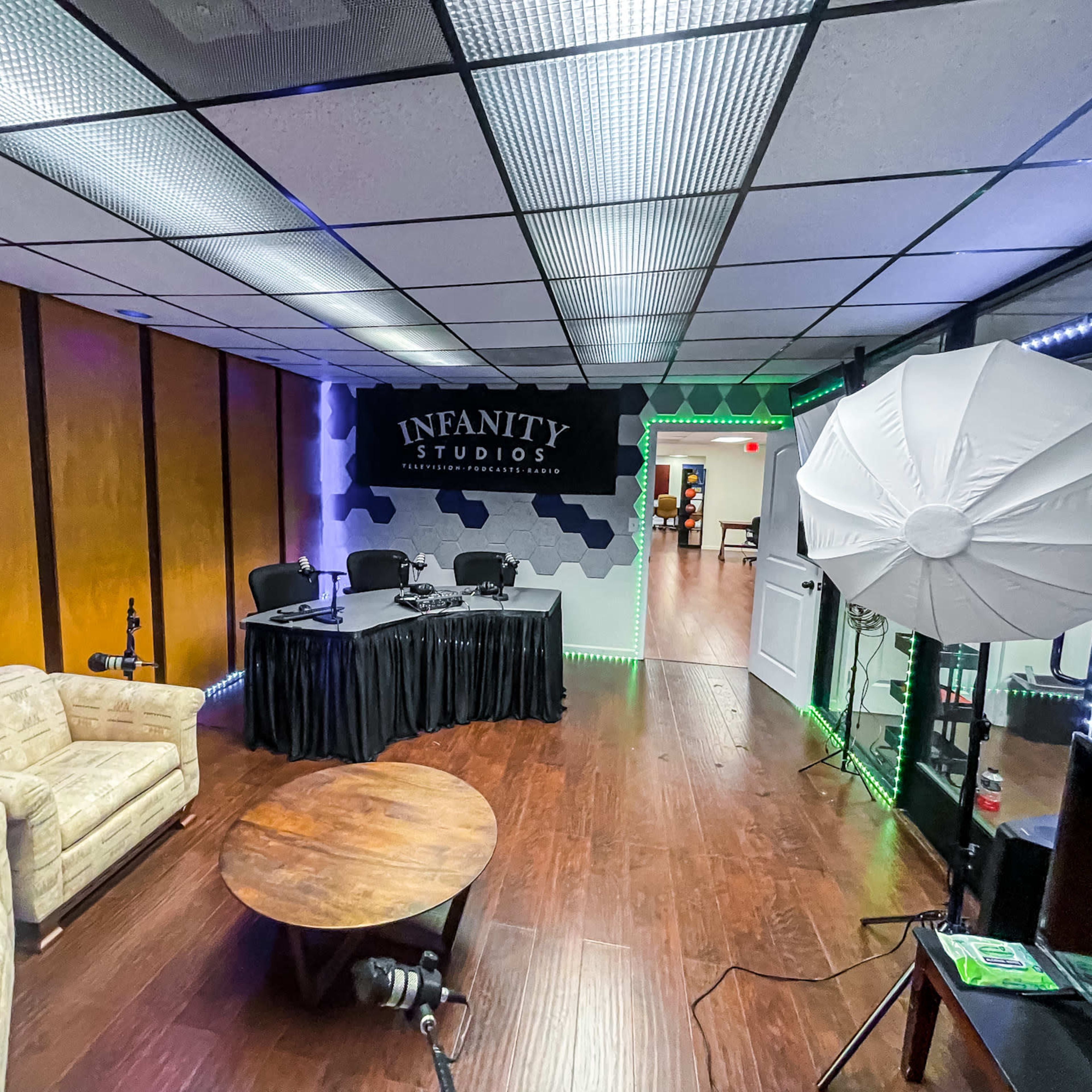 A studio room featuring a table with chairs, a circular table, and studio lighting equipment.