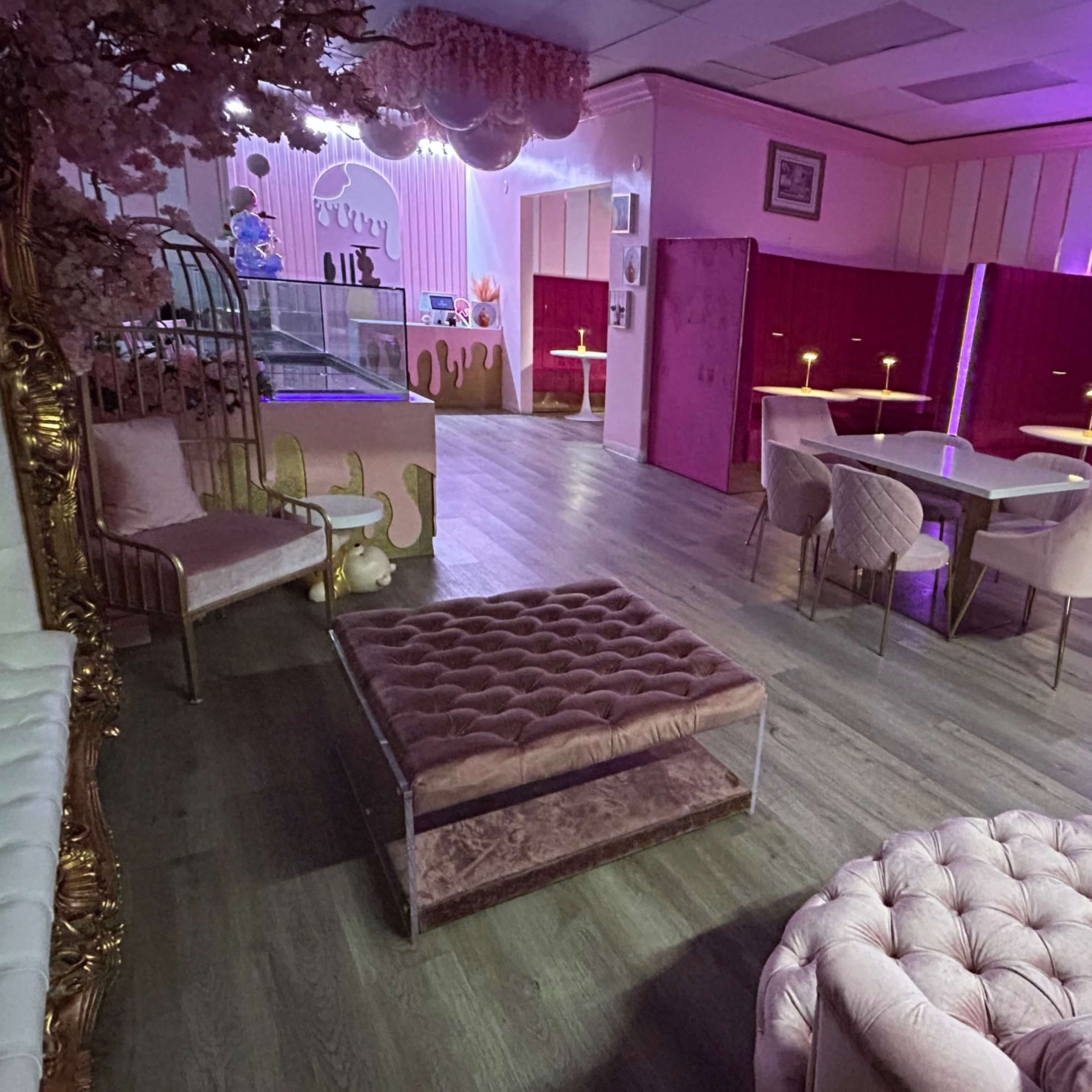 A pink-themed lounge area with plush furniture, elegantly arranged tables, and soft lighting.