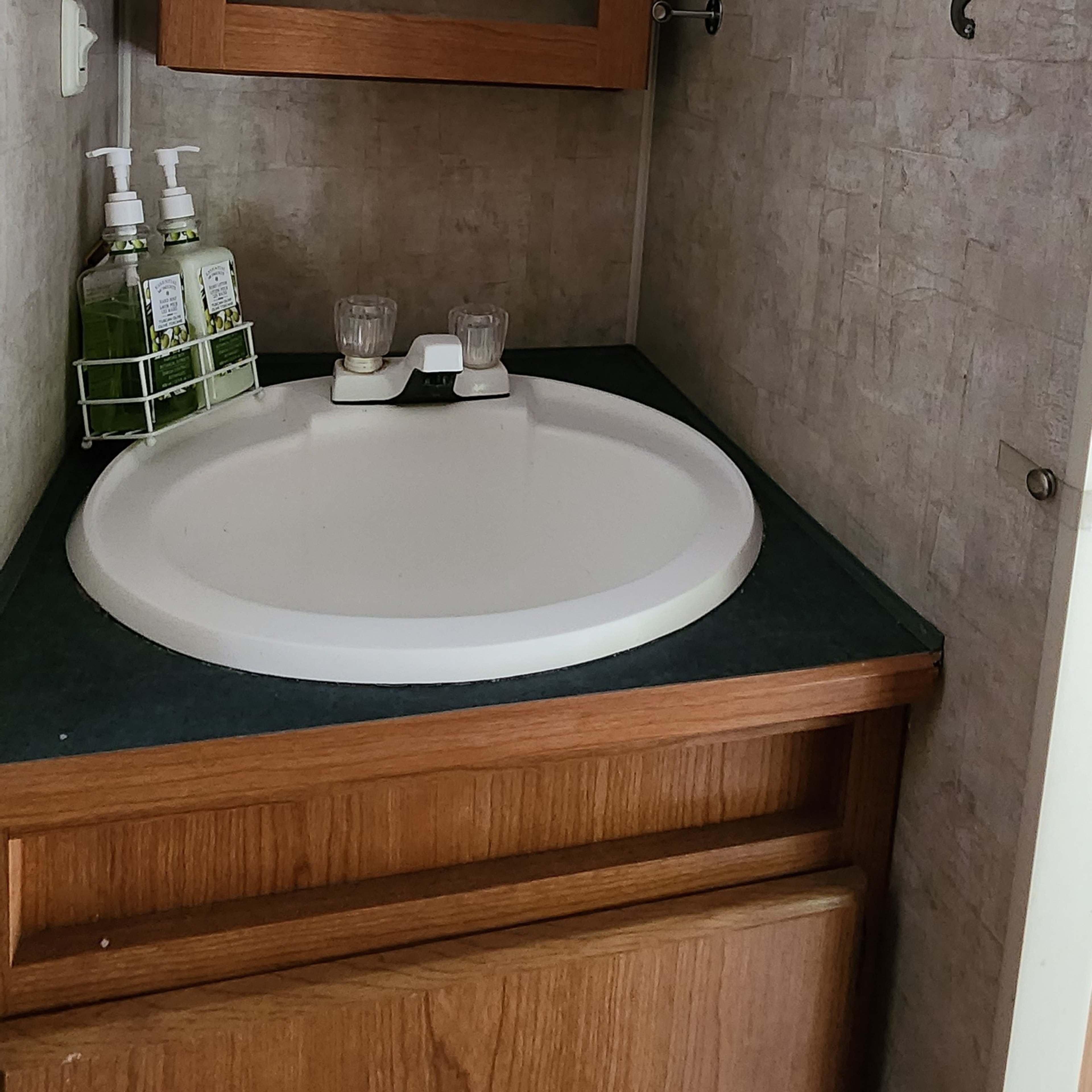 A small bathroom with a circular sink, a wooden cabinet below, and a mirror mounted above.