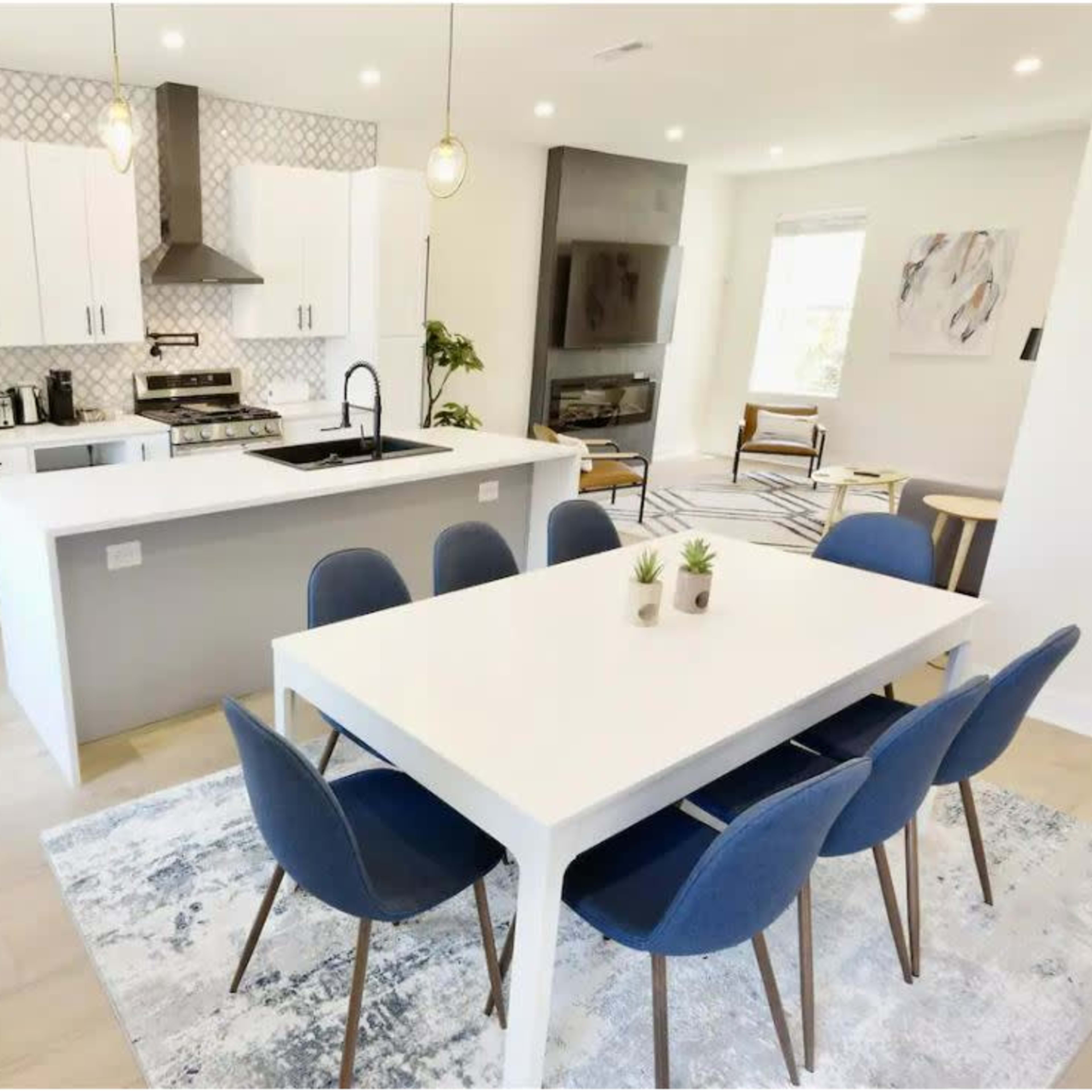 A modern kitchen and dining area with white cabinetry, a large island, and a table set for eight.
