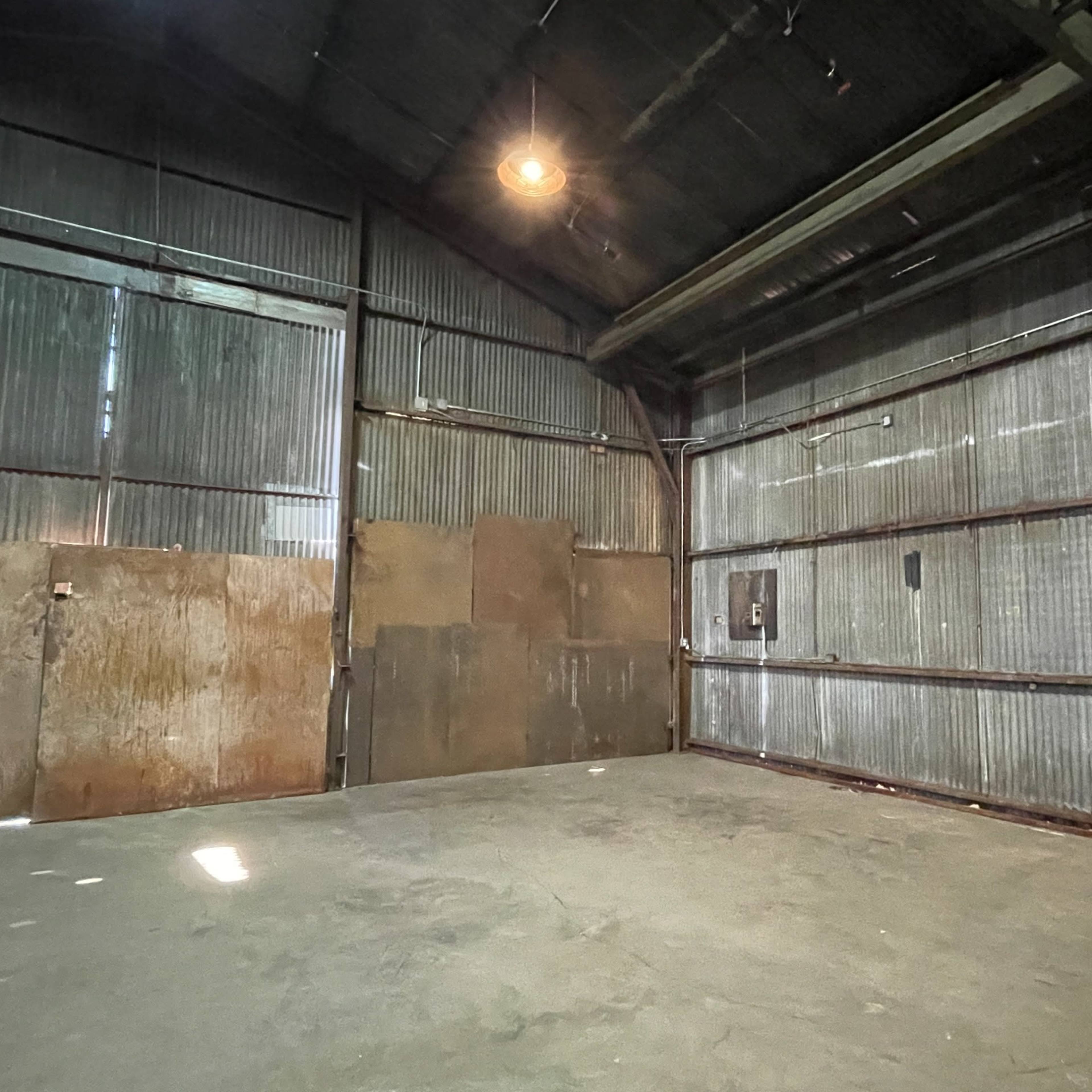 A large, empty industrial warehouse with corrugated metal walls and a high ceiling.