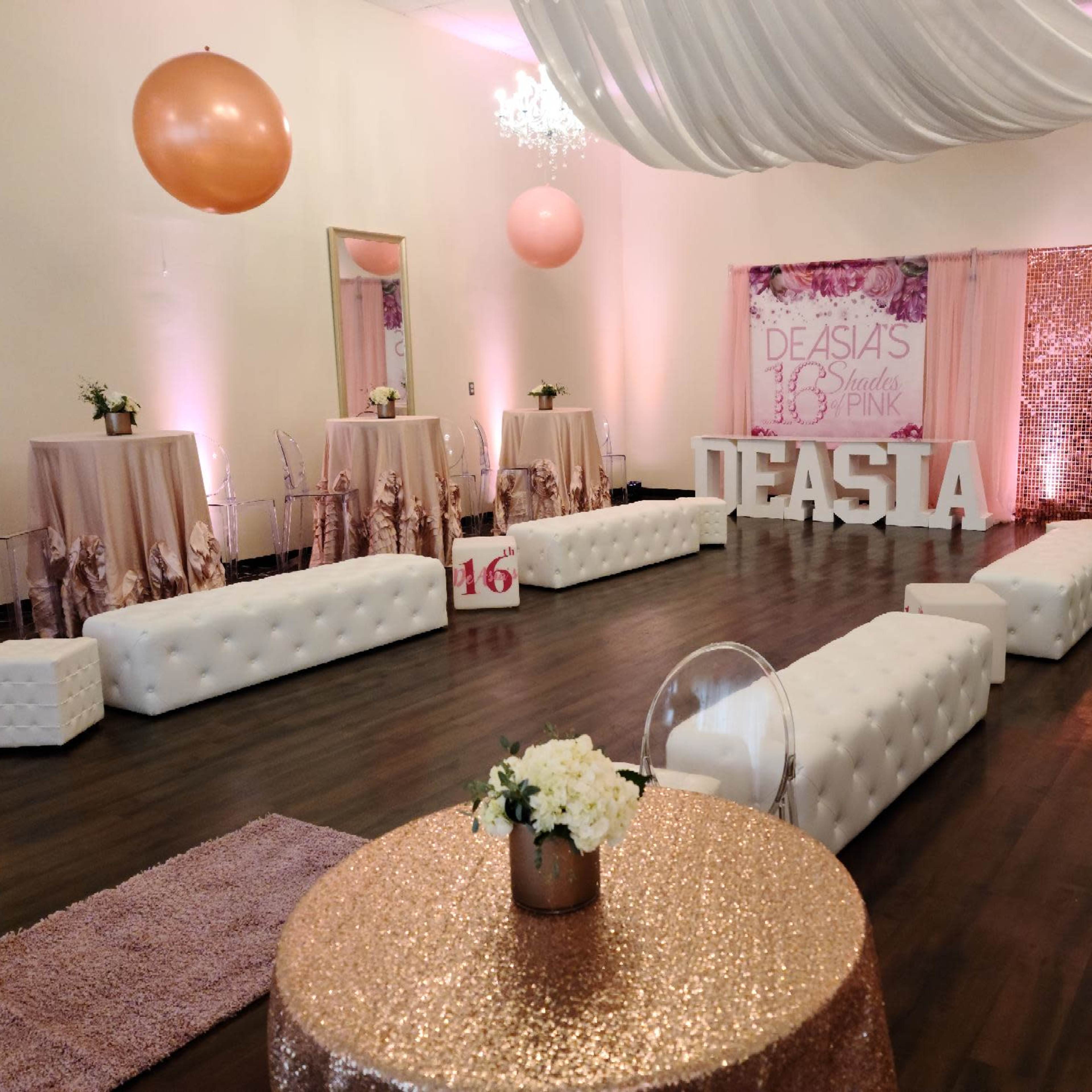 A decorated event space with white tufted sofas, pink balloons, and a "DEASIA 16" sign against a sequin backdrop.