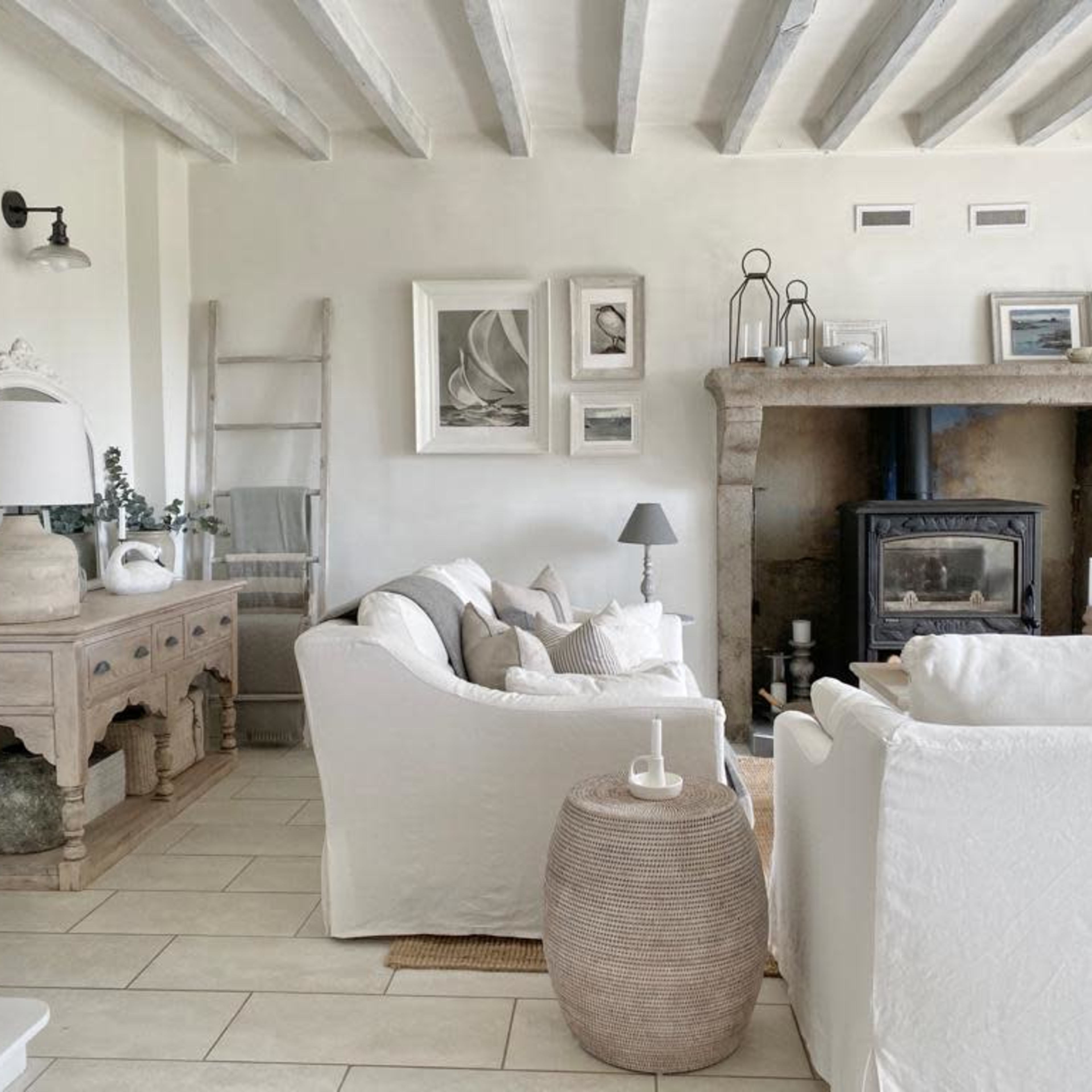 The scene shows a light-colored living room with a stone fireplace, white sofas, and wooden accents.