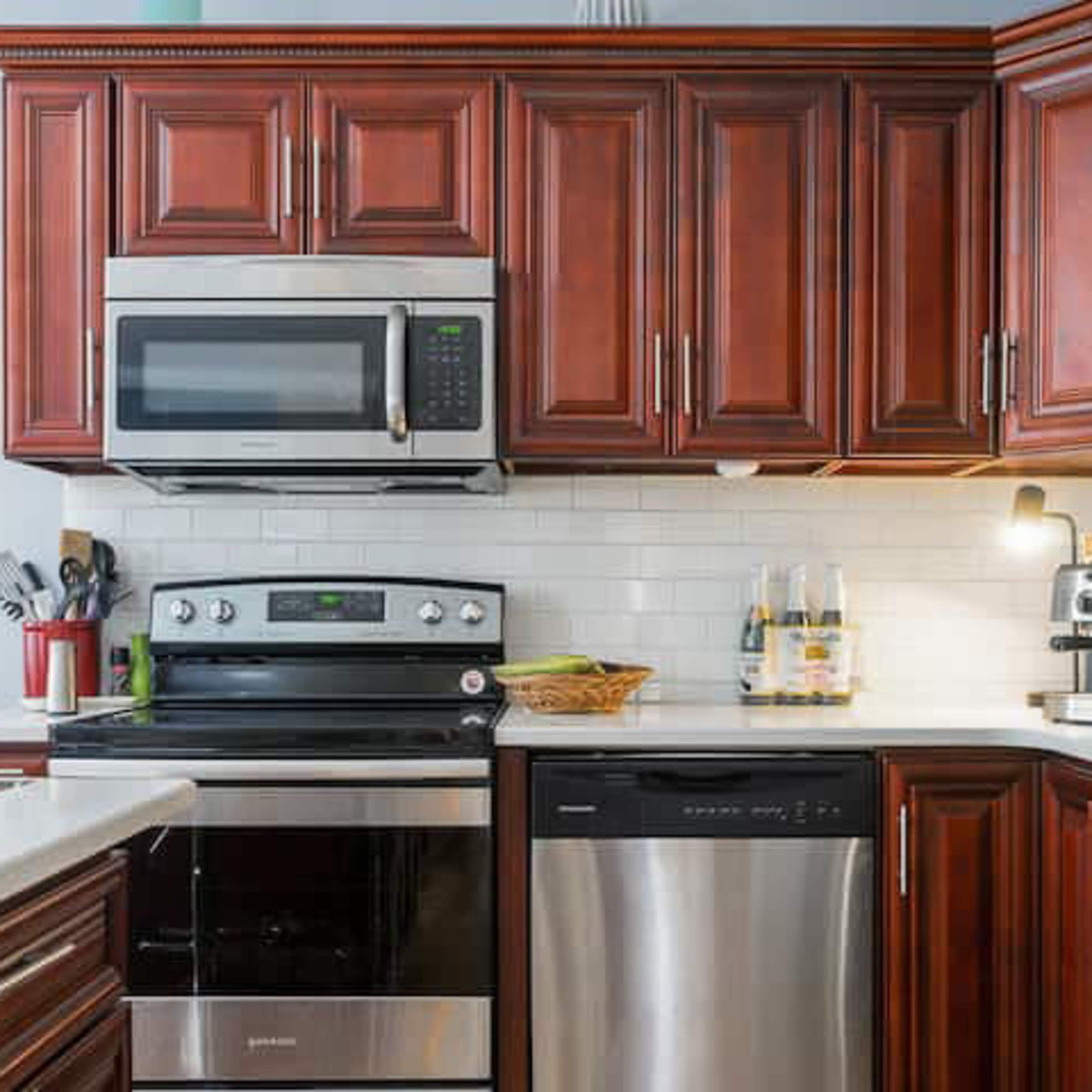 A kitchen with dark wooden cabinets, stainless steel appliances, and a white countertop.