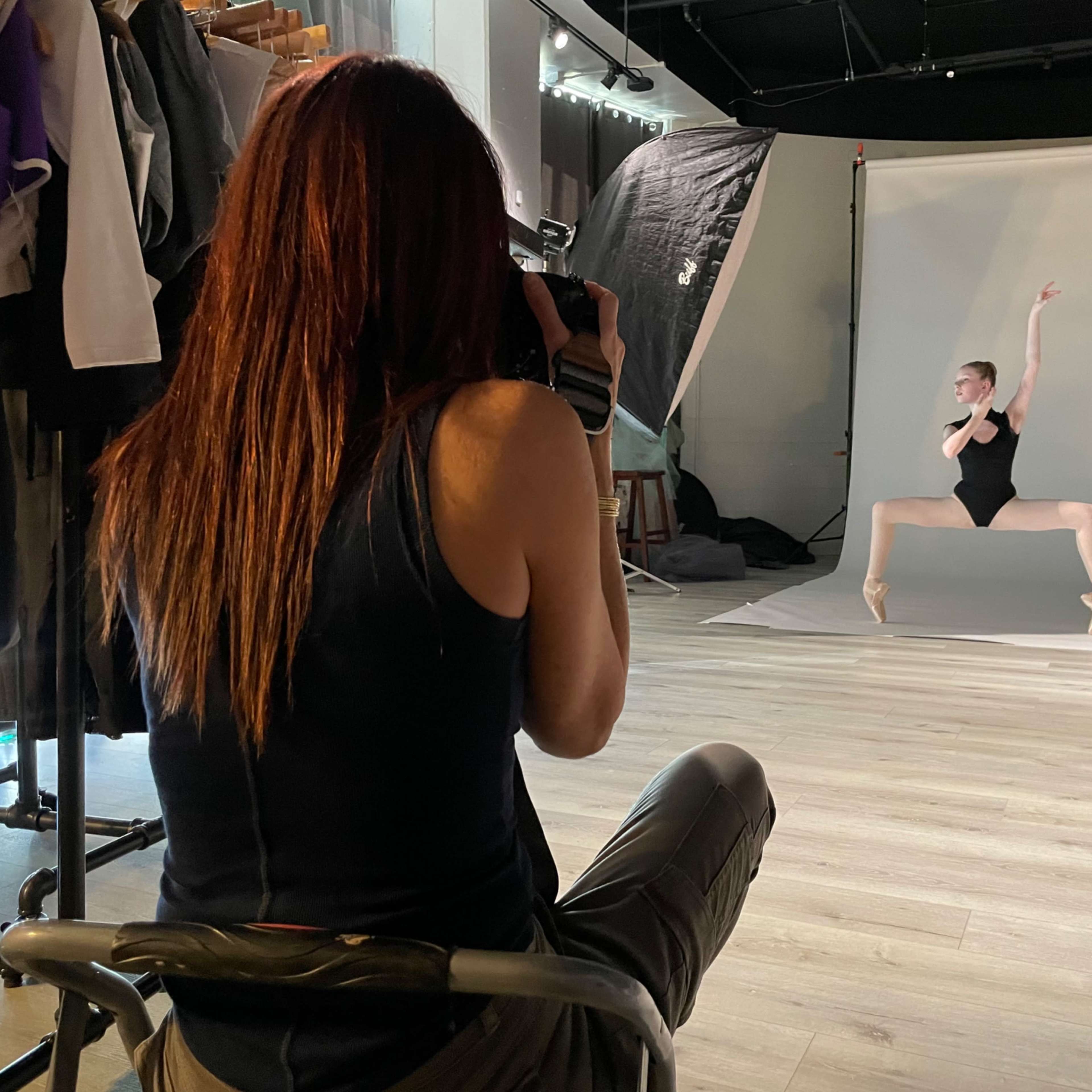 A photographer captures a dancer striking a pose in a studio setting.