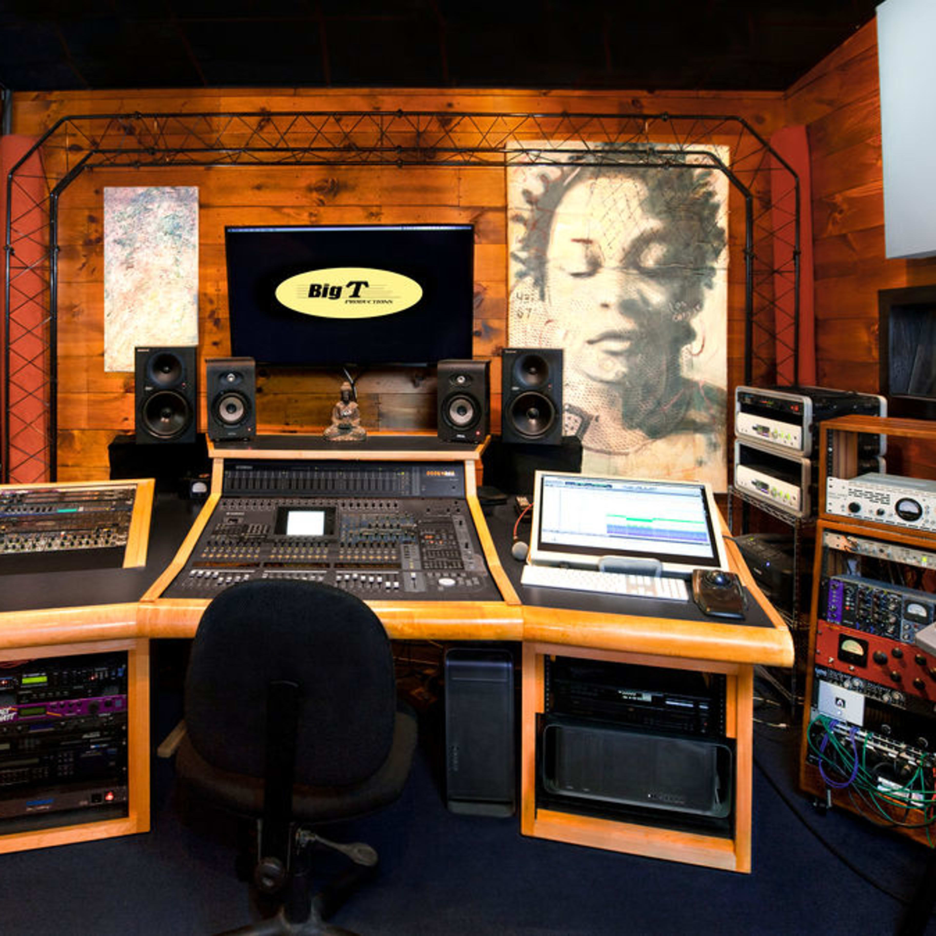 A well-equipped recording studio with a central mixing console, speakers, and various audio equipment arranged within wooden paneling.