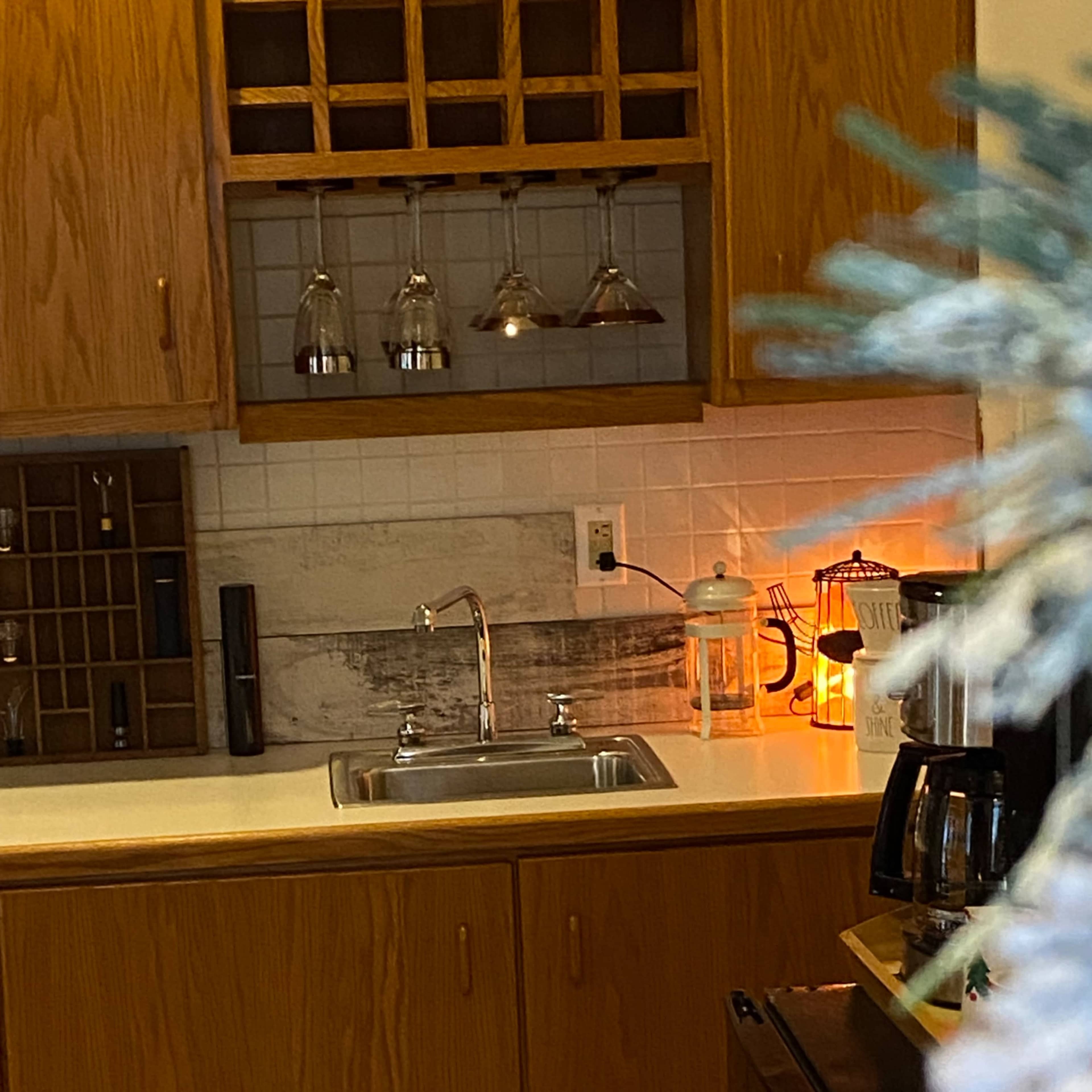 A kitchen with wooden cabinets, a sink, a coffee maker, and a decorative lantern.
