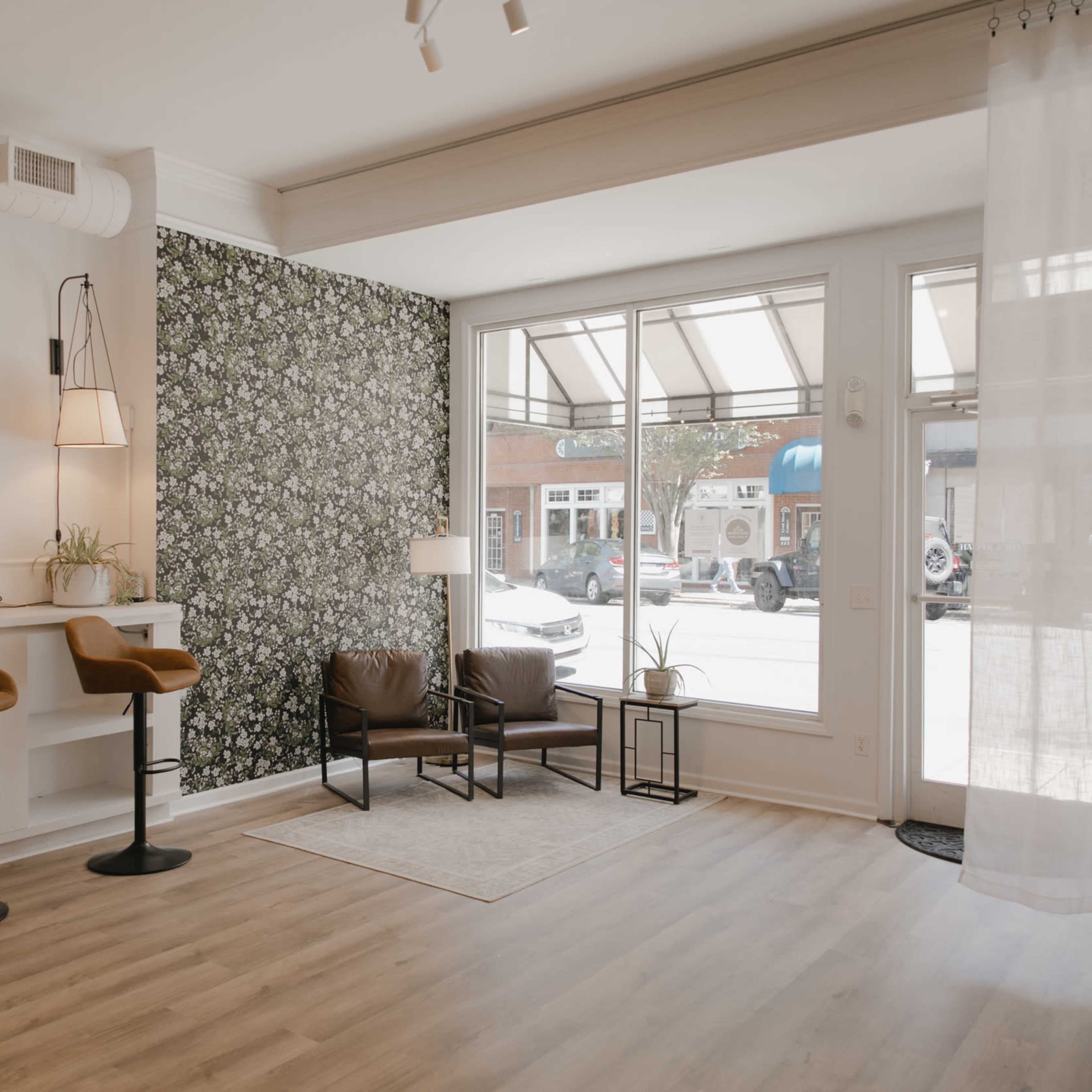 A modern interior of a boutique space with bar seating, a patterned accent wall, and large windows allowing natural light to enter.