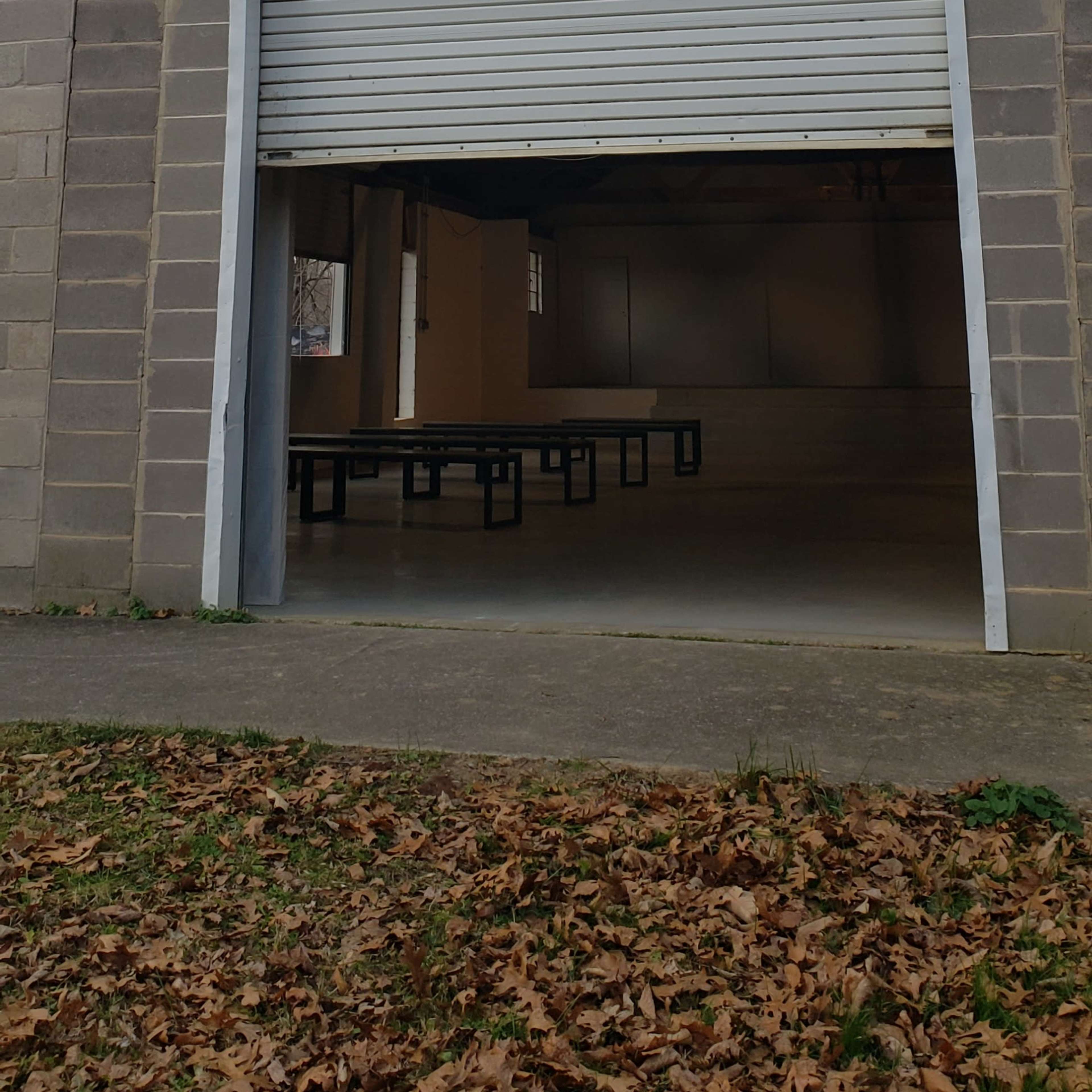 The exterior of a metal building with a large wooden cross above a closed garage-style door.