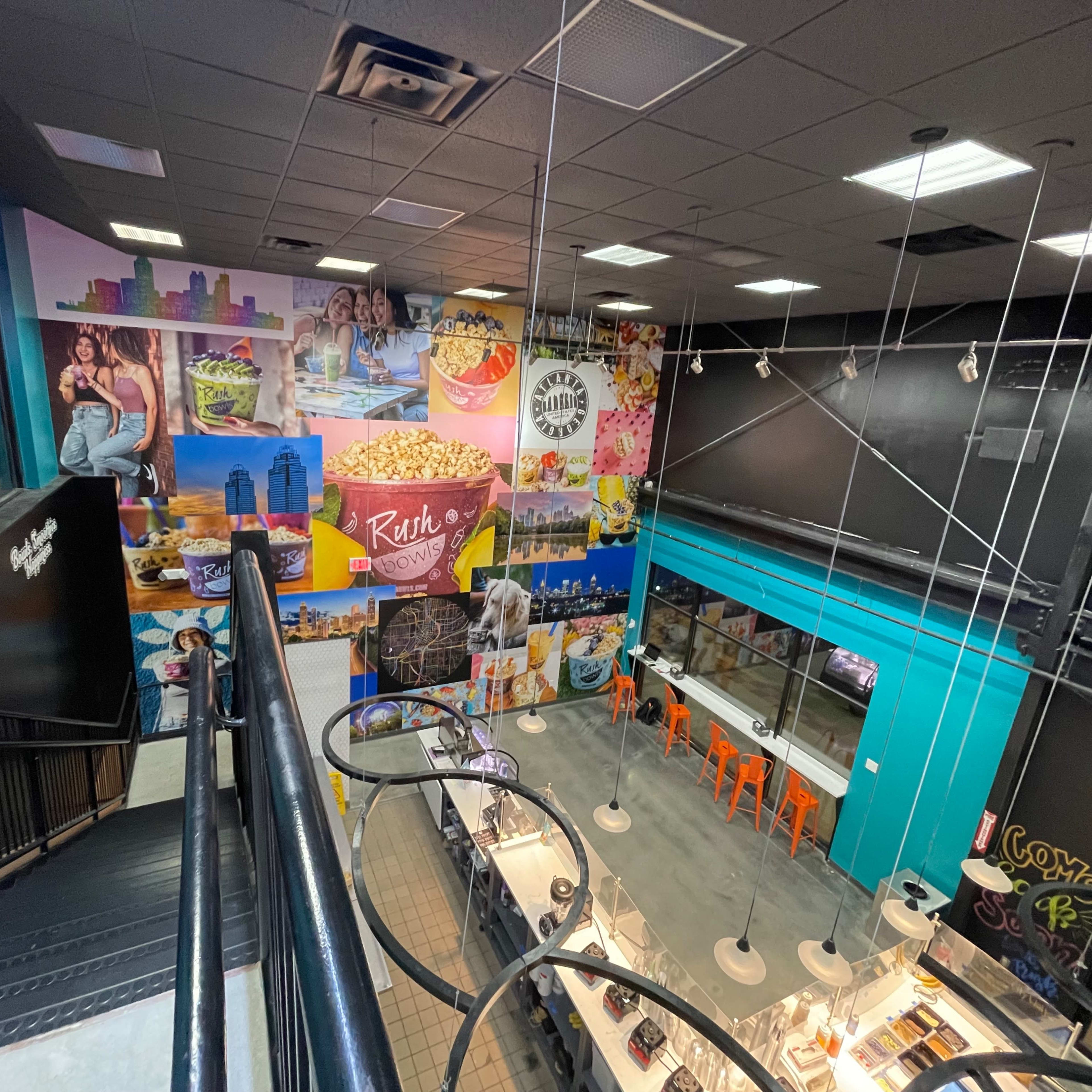 An interior of a vibrant food establishment featuring colorful wall murals and a spacious seating area with bright chairs.