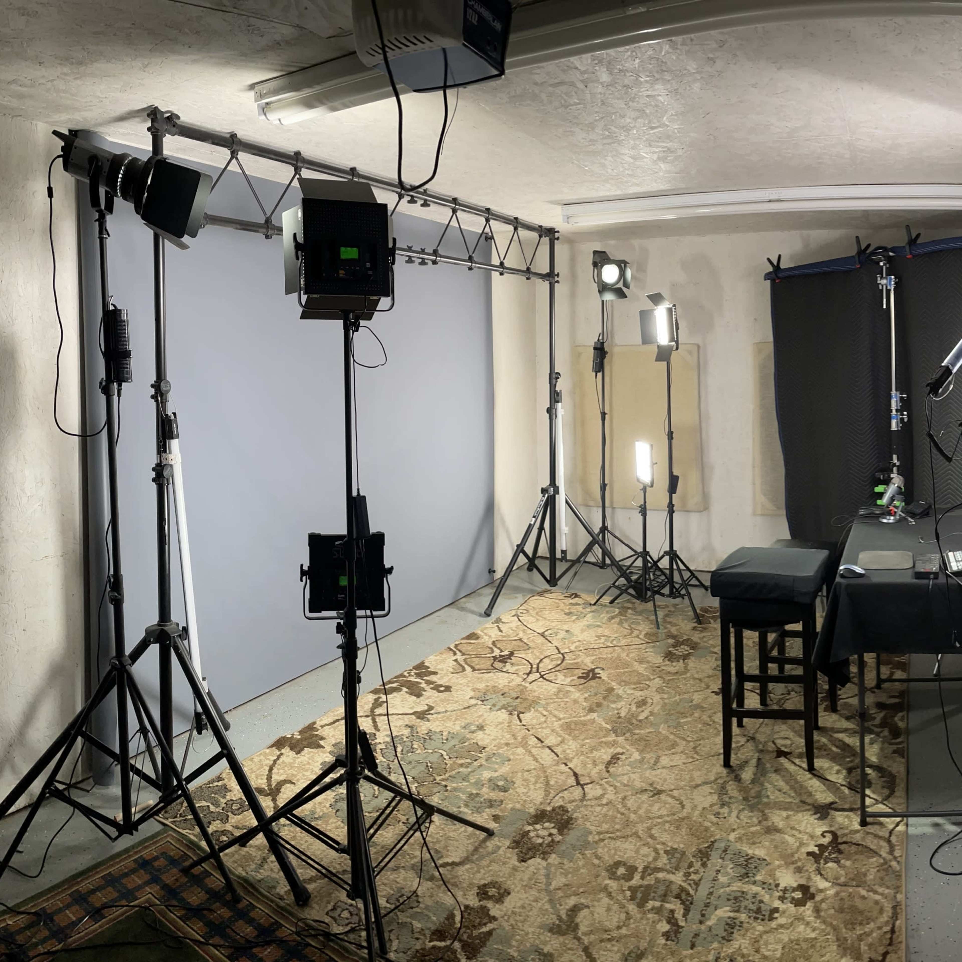 A photography studio setup with various lighting equipment, a table covered with a black cloth, and a backdrop.