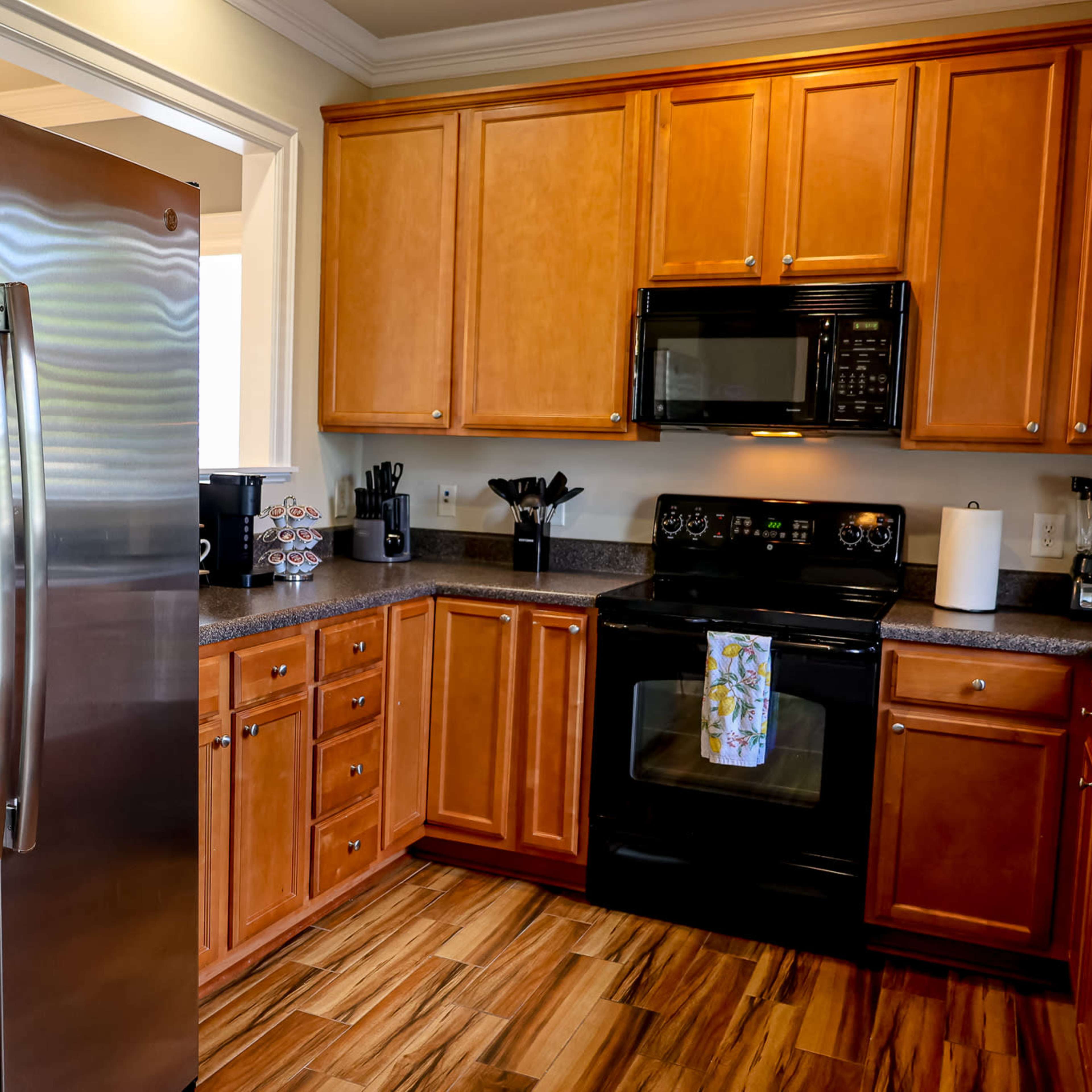 A kitchen with wooden cabinets, stainless steel appliances, and a countertop with various kitchen tools and devices.