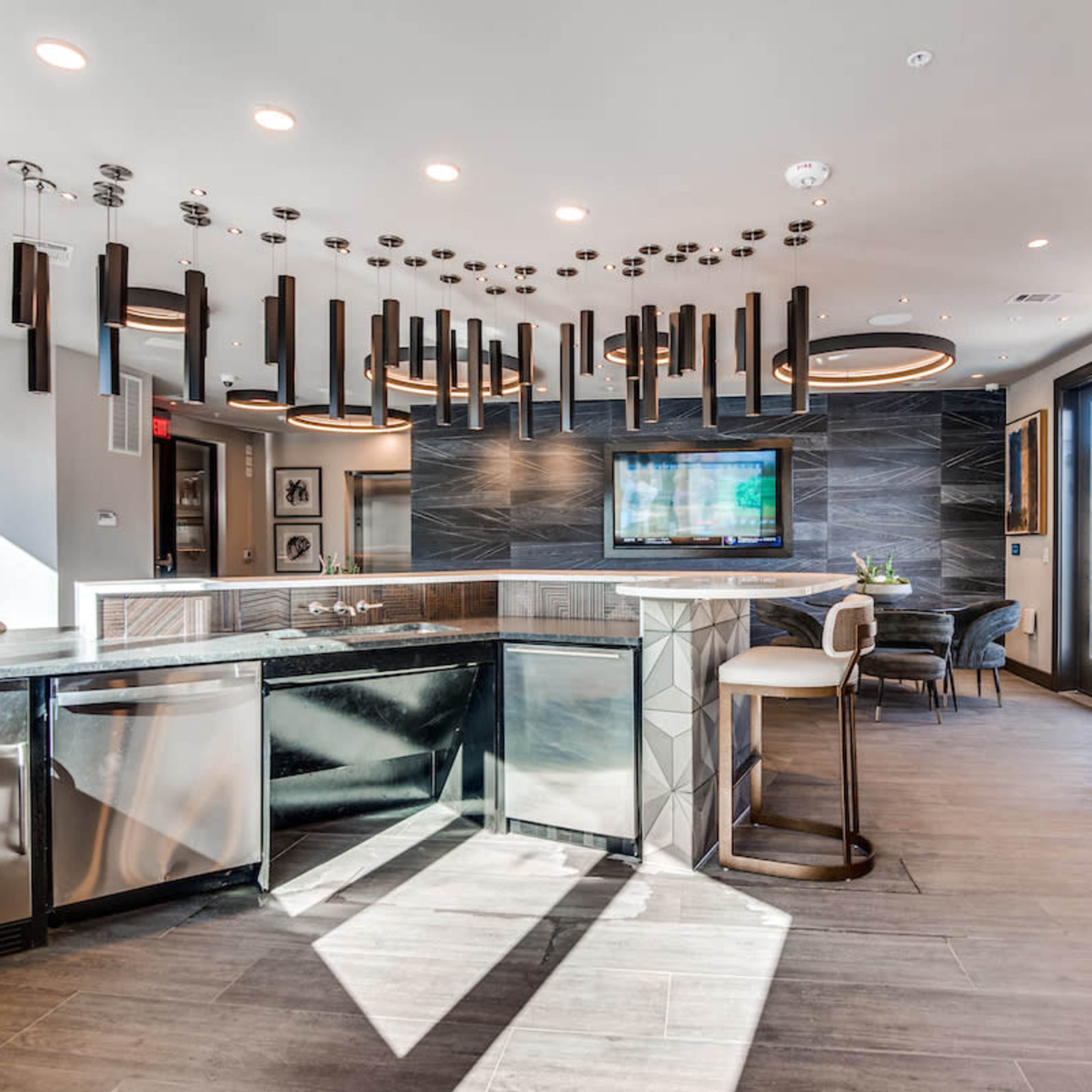 A modern kitchen with sleek cabinetry, large windows, and decorative pendant lighting.
