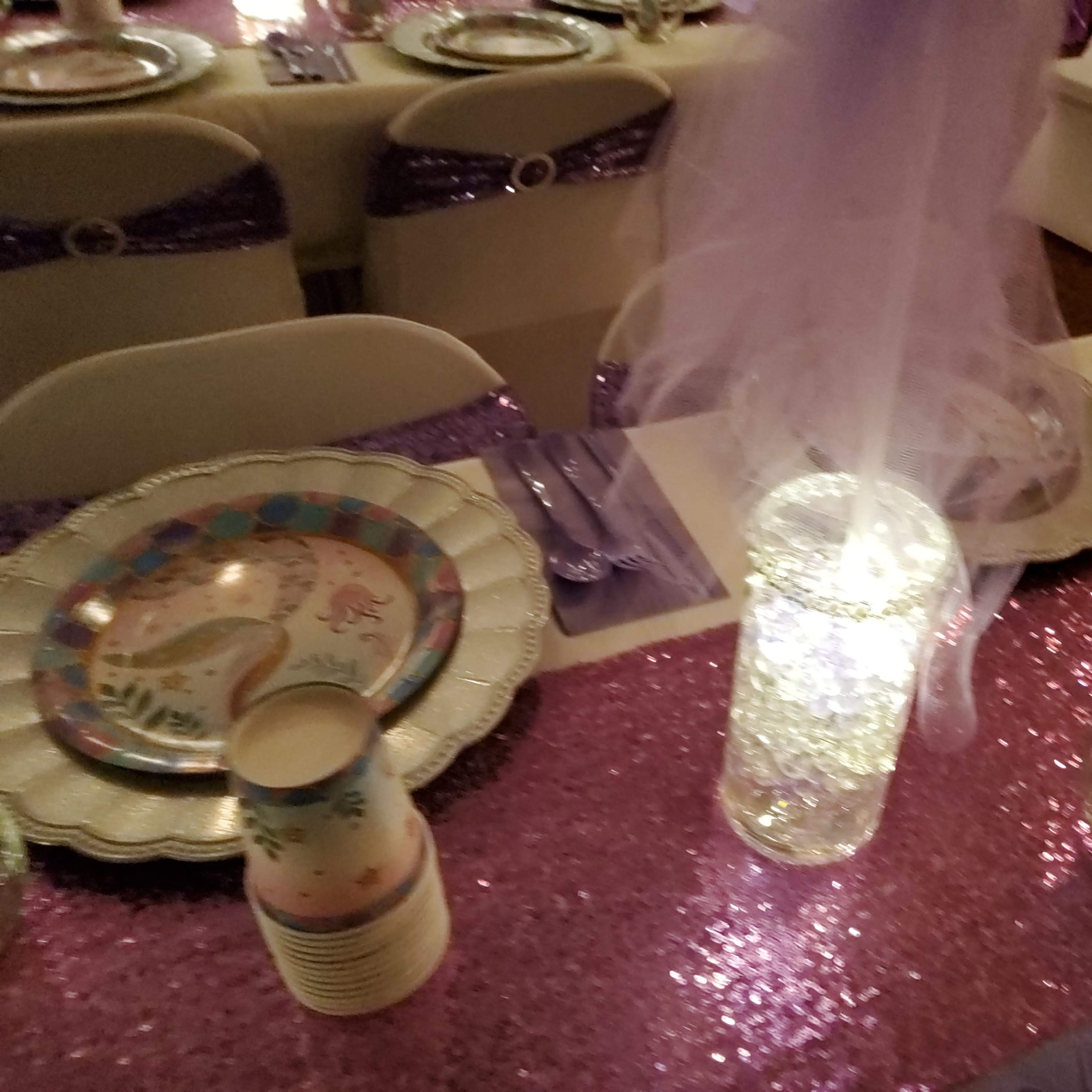 A table set for a party features sparkling decorations, colorful plates, and shimmering tablecloths.