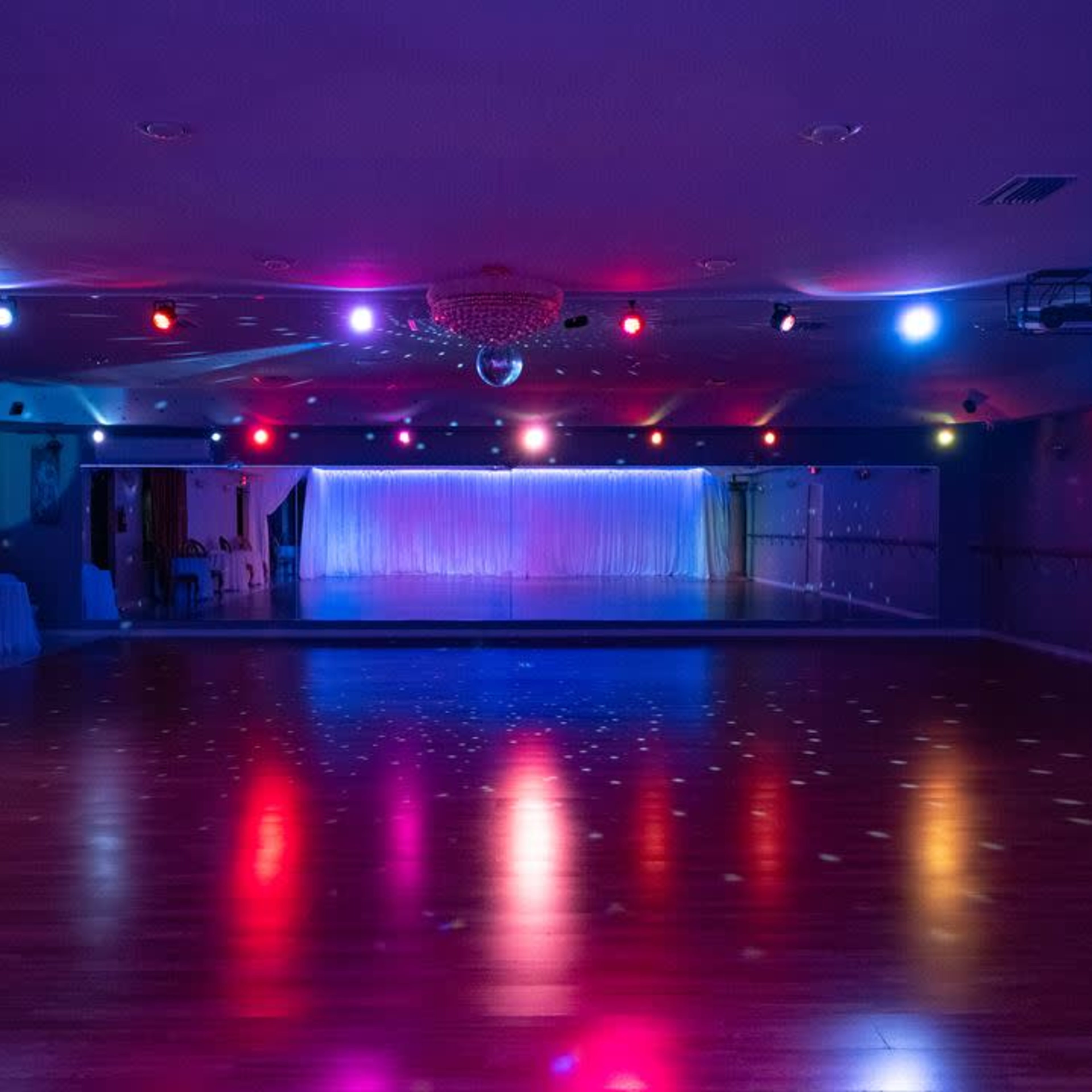A brightly lit dance studio with colorful spotlights and reflective surfaces on the floor.