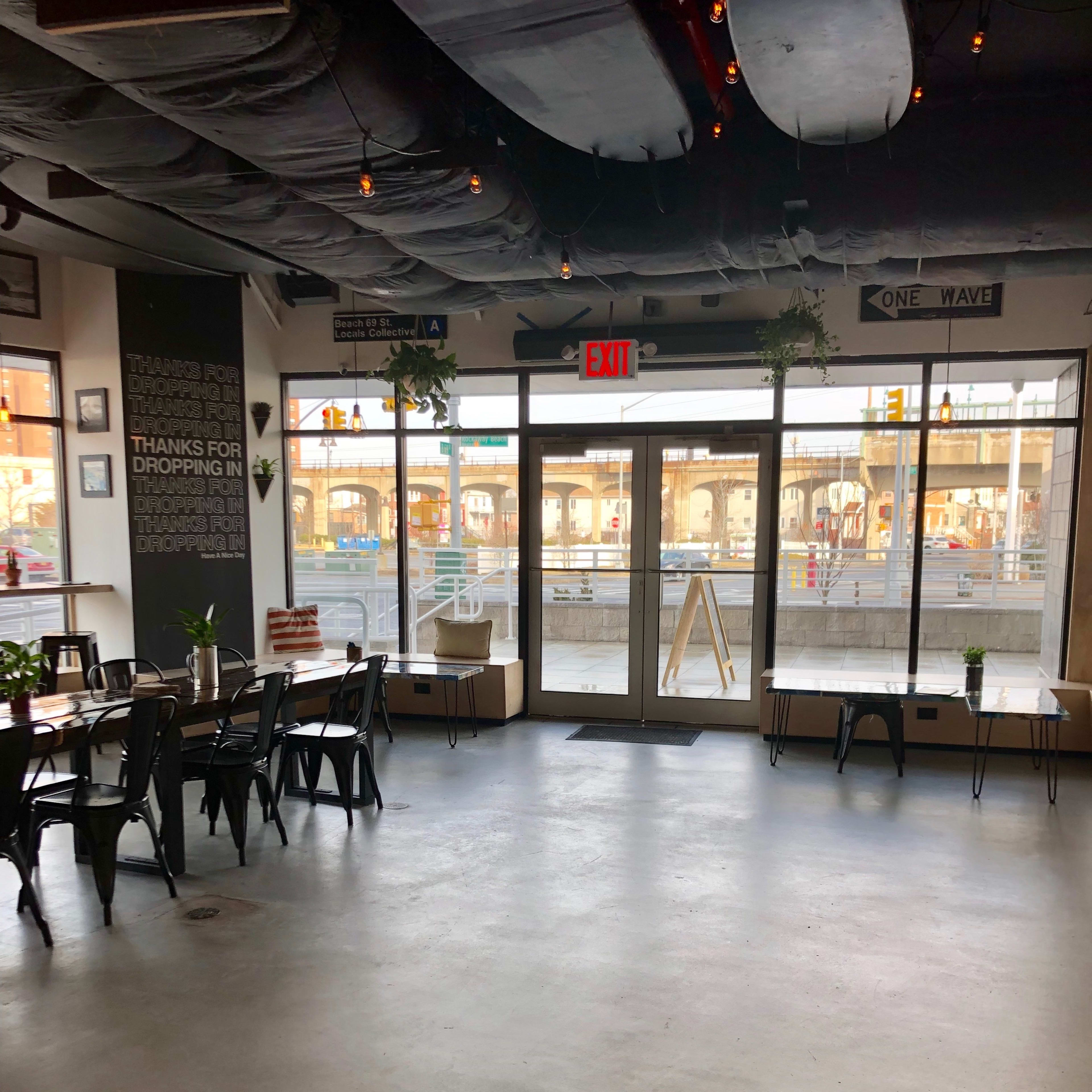 A spacious café interior with seating arrangements and large glass doors leading to an outdoor area.