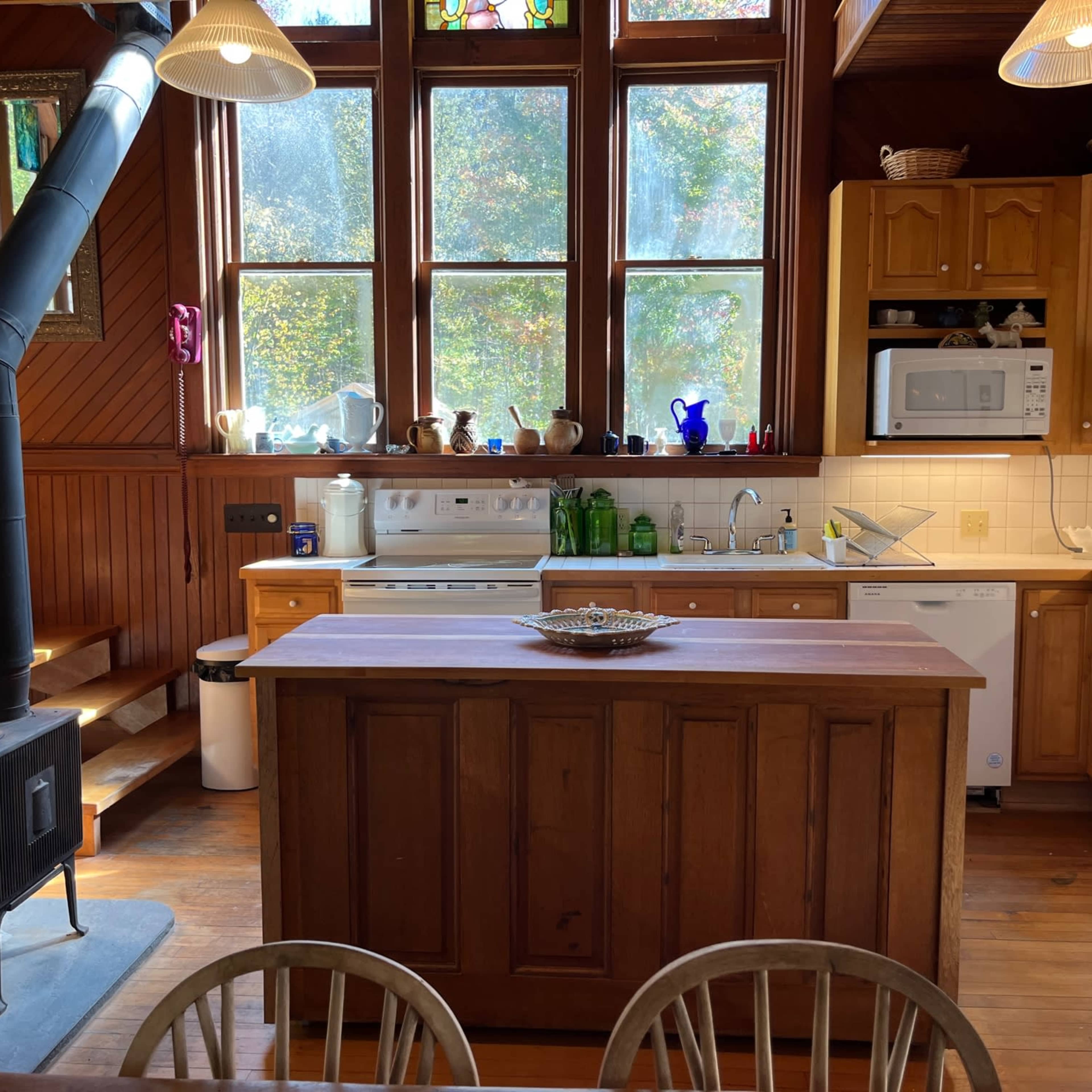 A kitchen with wooden cabinetry, a central island, and large windows that allow natural light to enter.