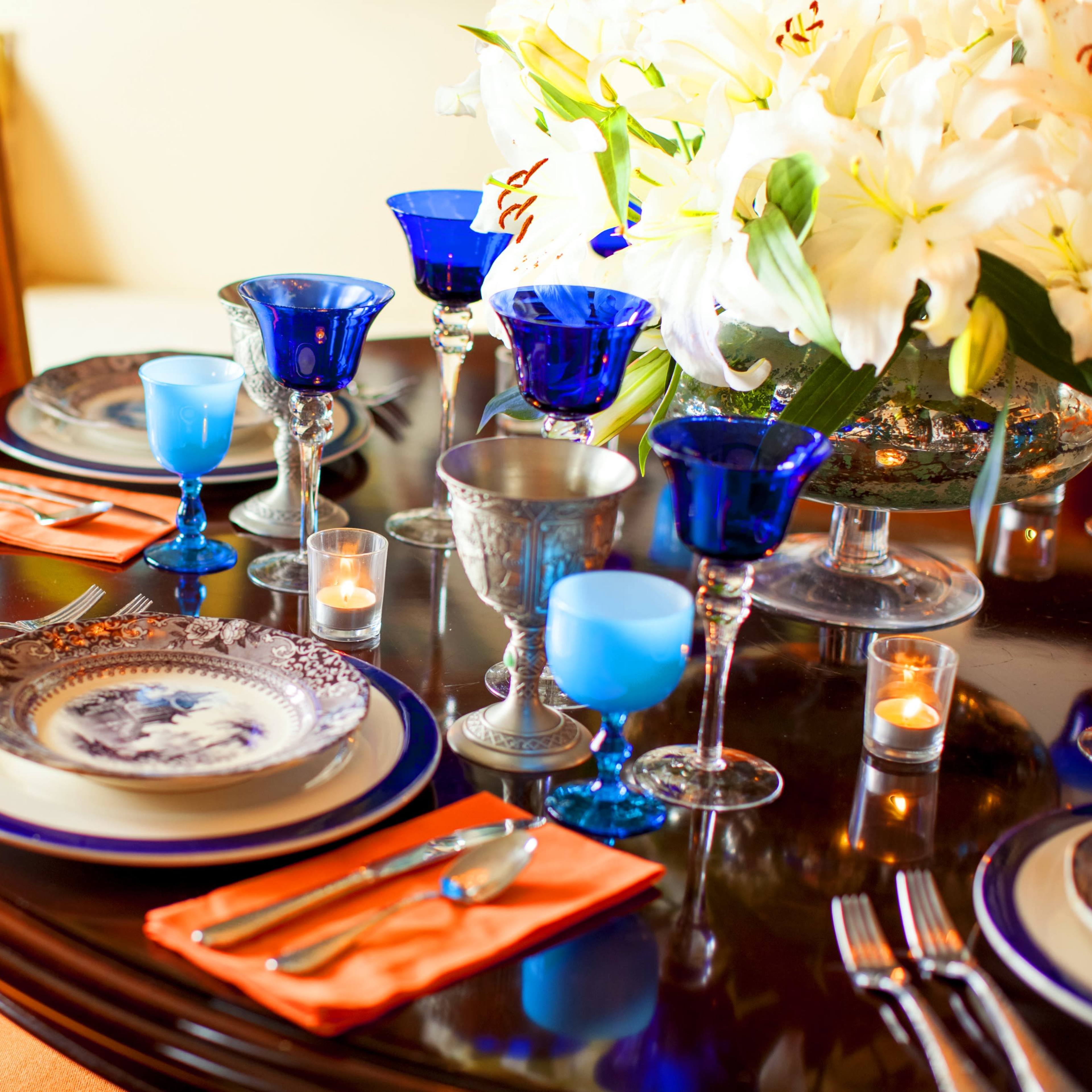 A elegantly set dining table featuring decorative plates, crystal glasses, and a floral centerpiece.