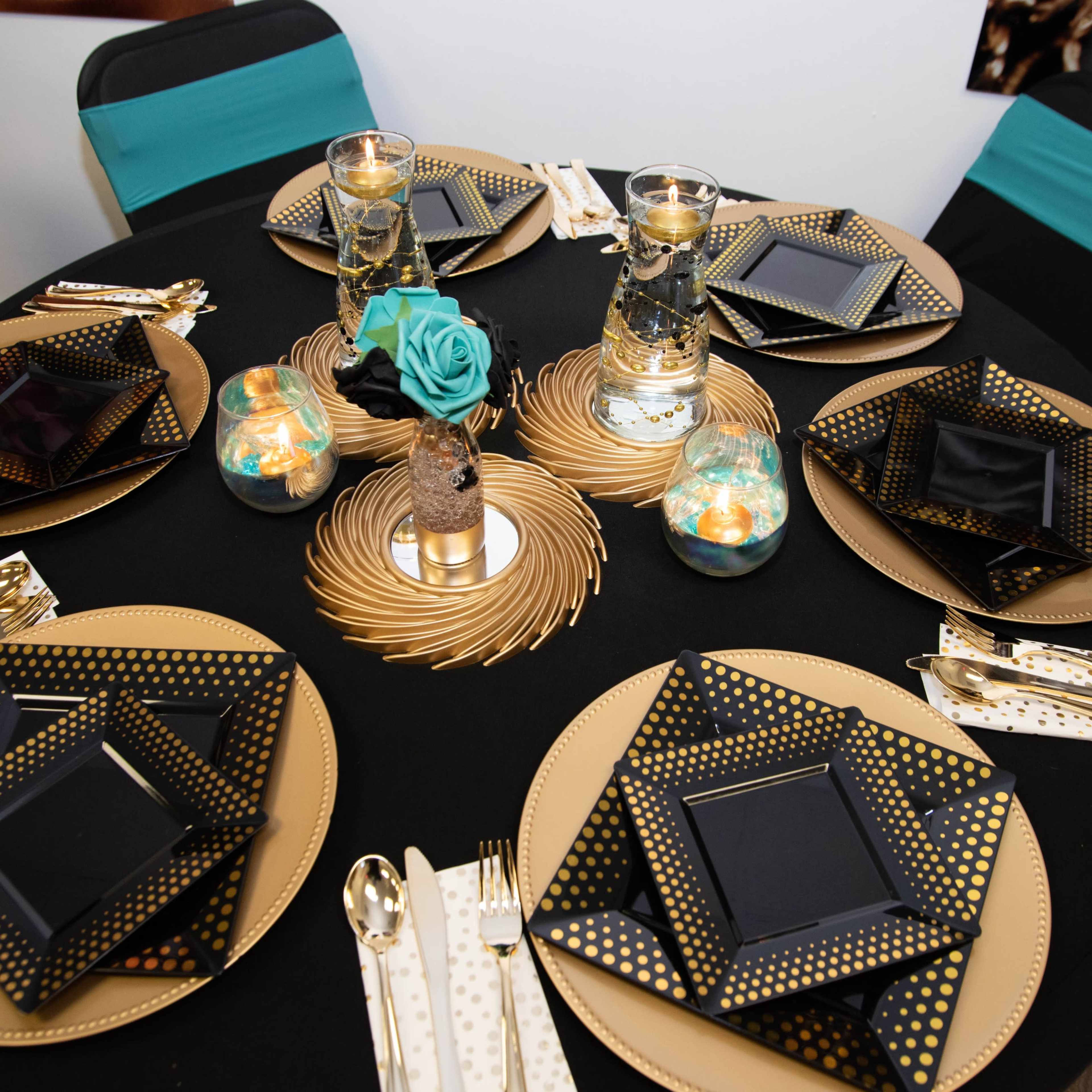 An elegantly set dining table with black and gold plates, decorative candles, and turquoise accents.
