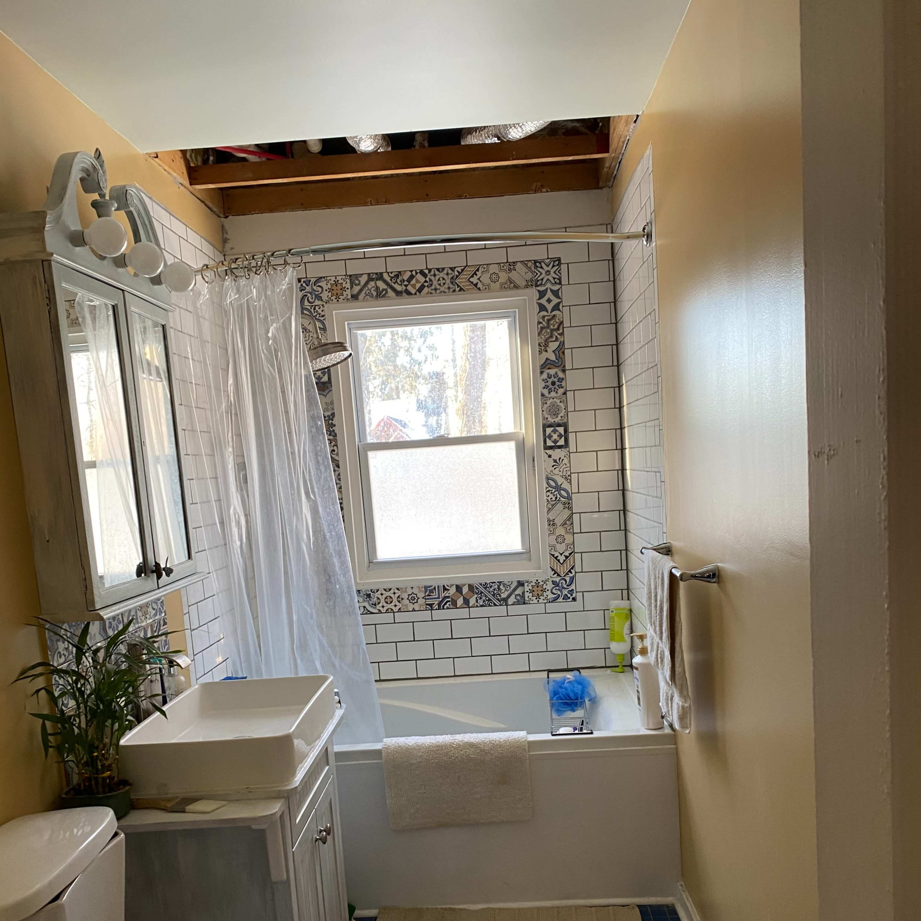 A bathroom with a bathtub, toilet, and sink, featuring white tiled walls and a blue tile floor.