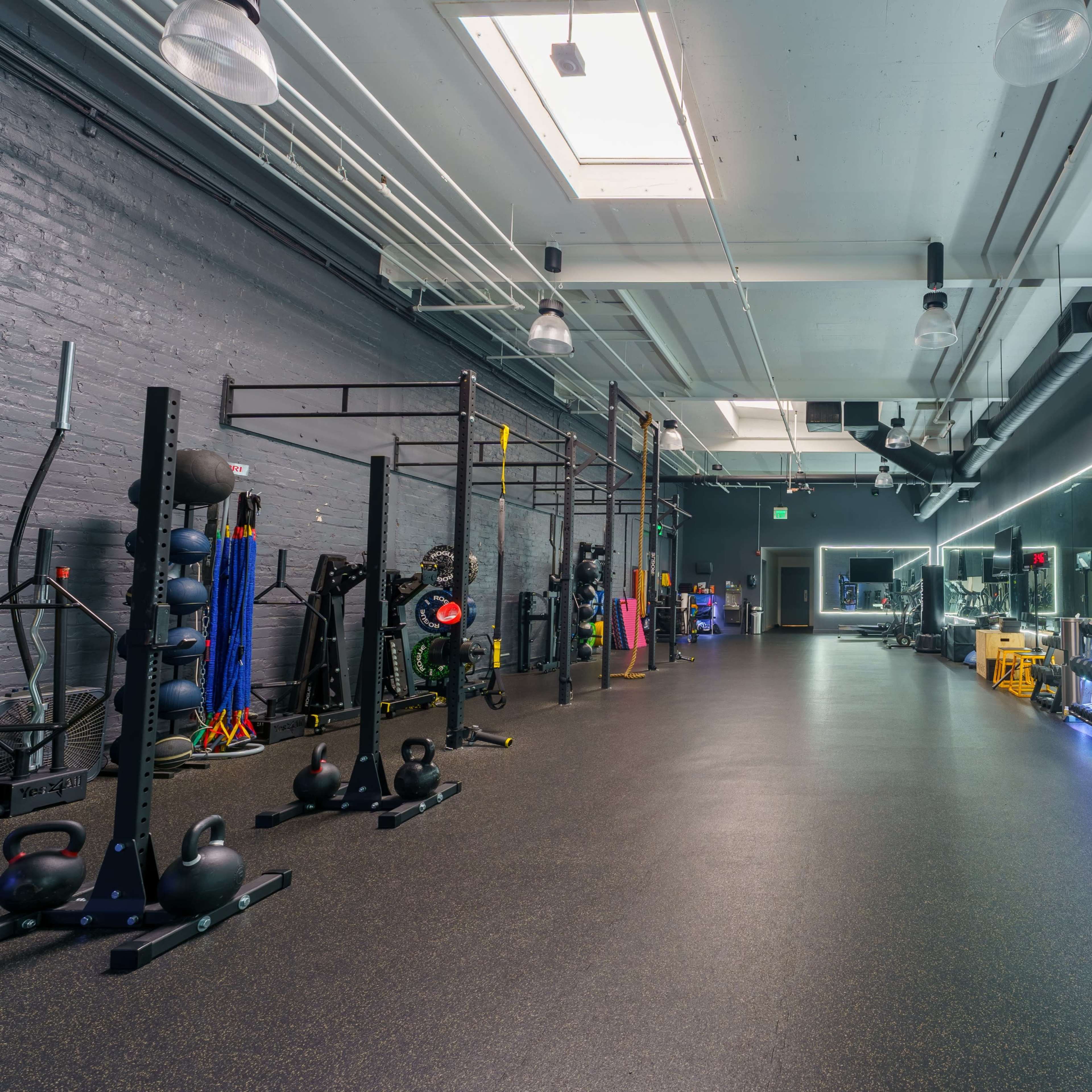 A spacious, well-equipped gym with various fitness equipment and exercise stations arranged along the walls.