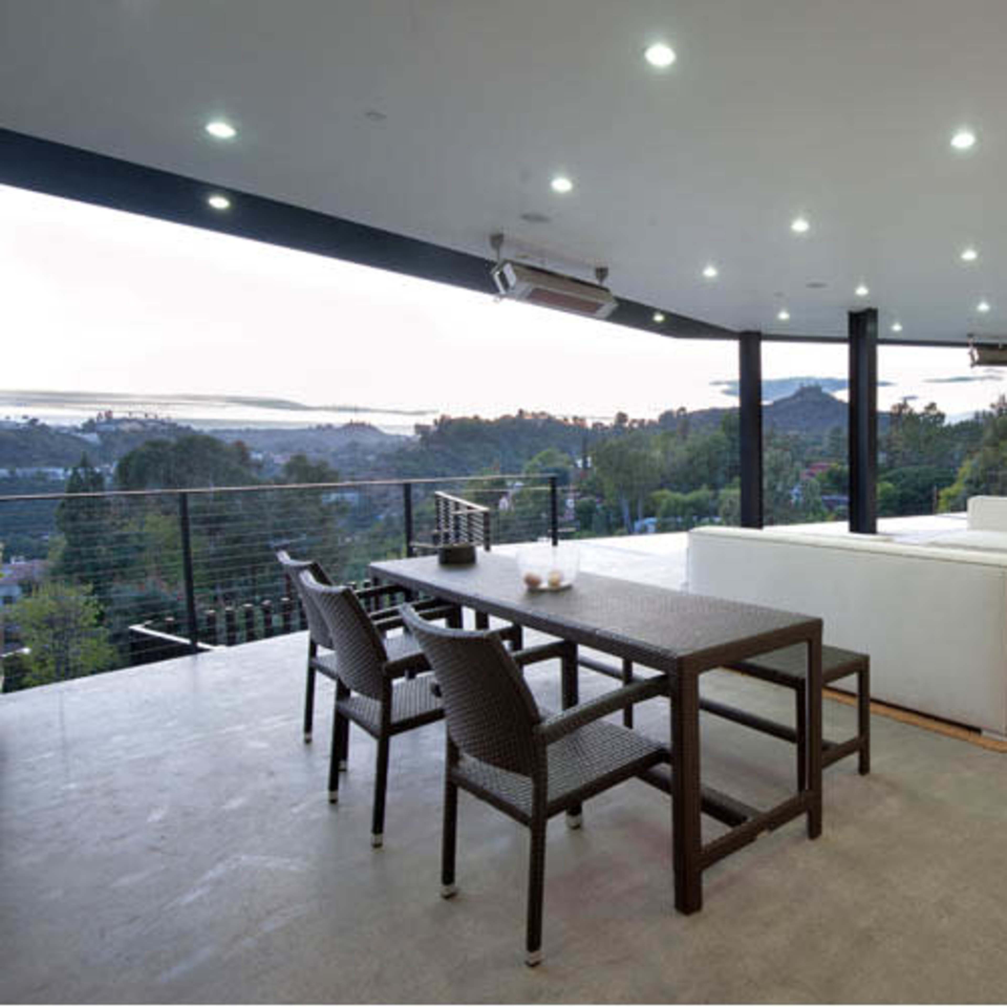 A modern, spacious living area with white furniture and large glass windows overlooking a scenic landscape.