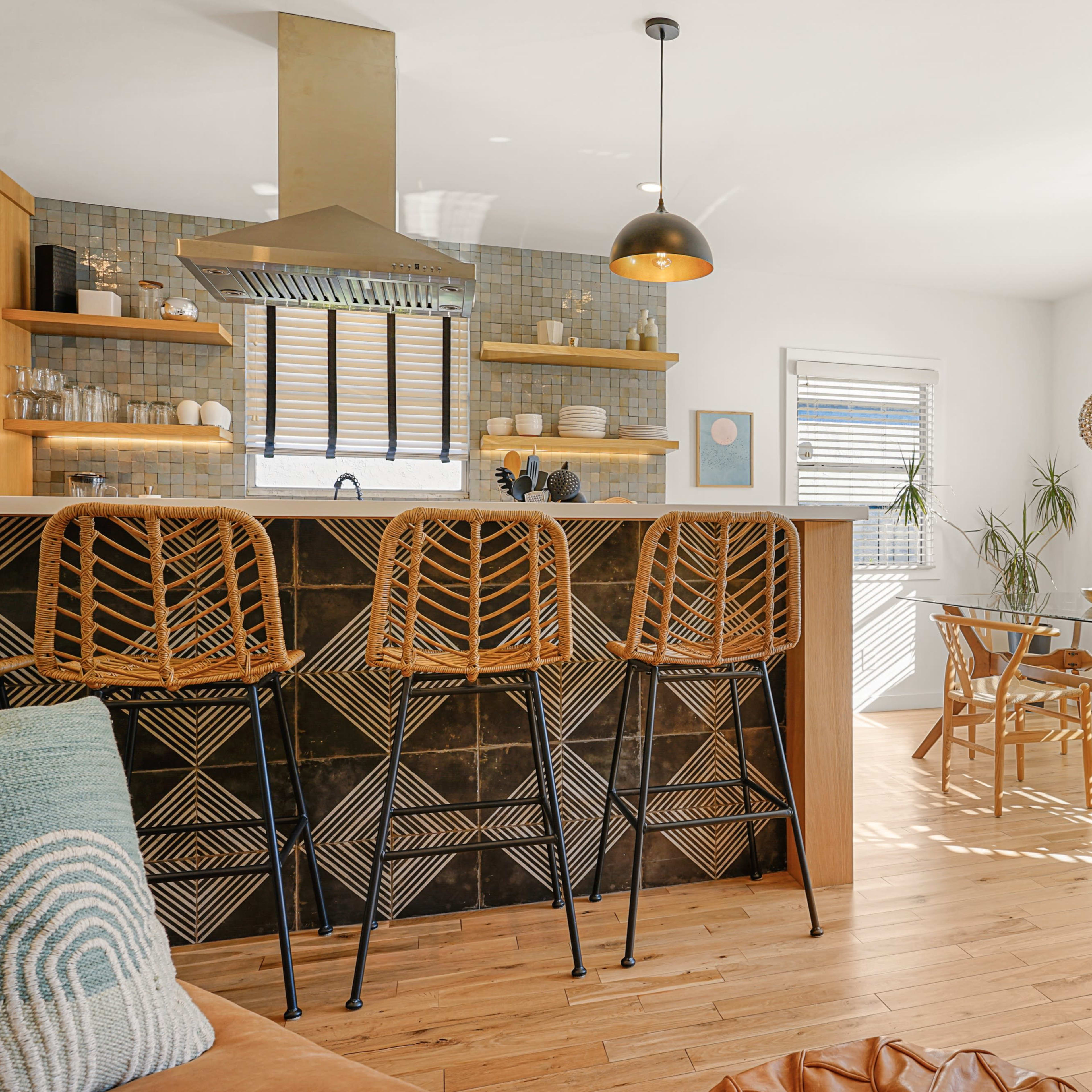 A bright, modern kitchen and dining area with wooden floors, a large kitchen island with bar stools, and a dining table set for a meal.