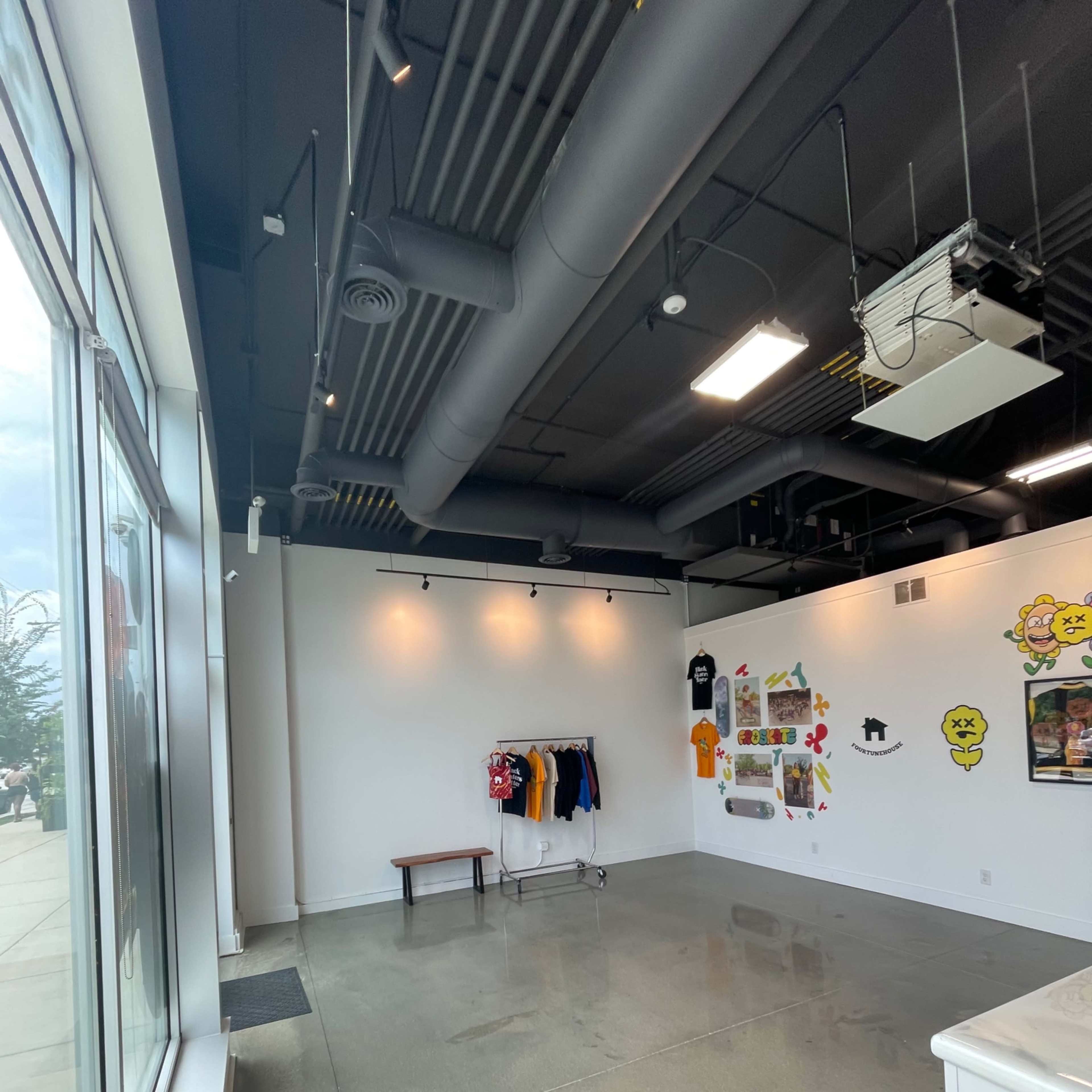 A spacious, empty room with a clothing rack, a bench, and a wall decorated with colorful art and graphics.