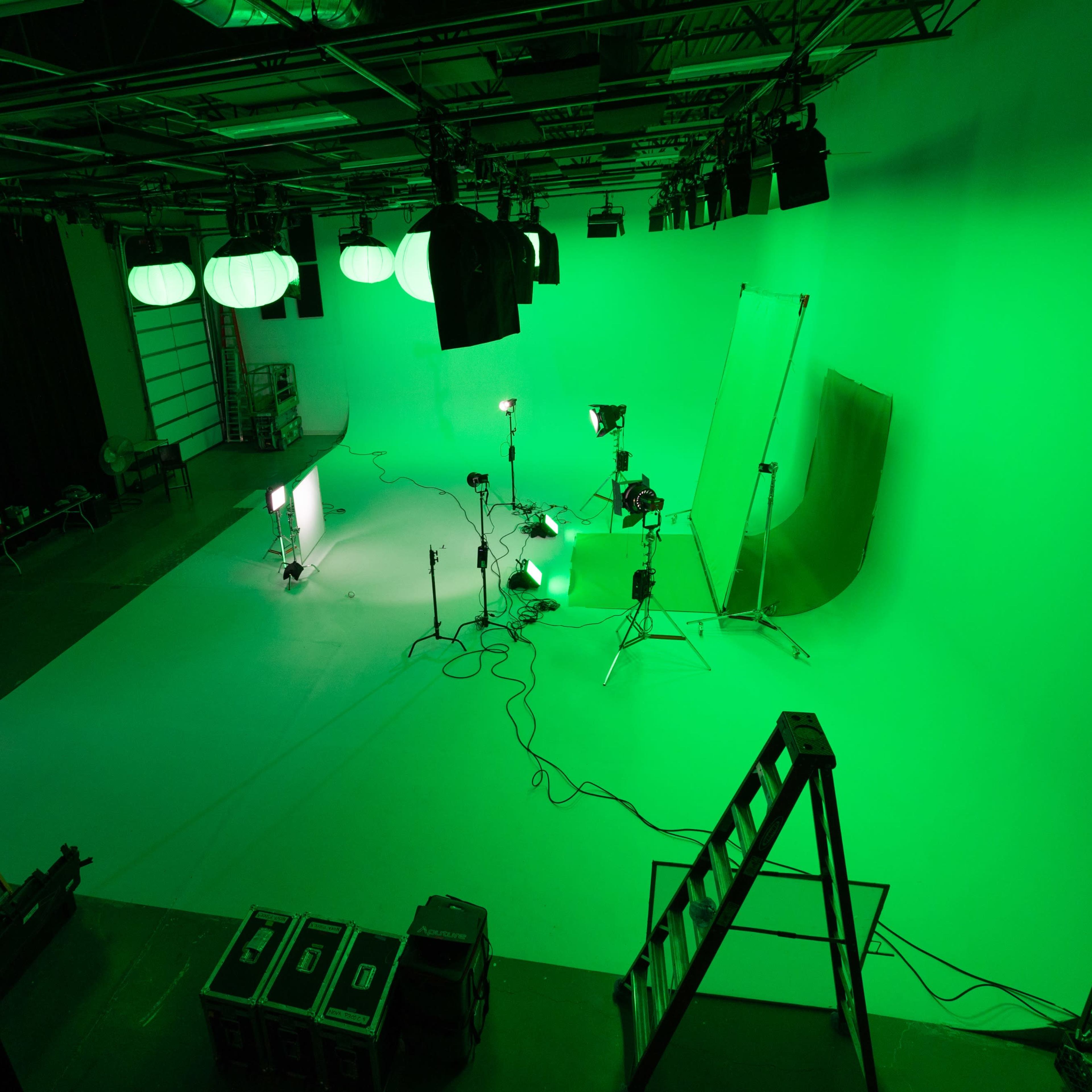 A green studio setup with lighting equipment and a blank backdrop.