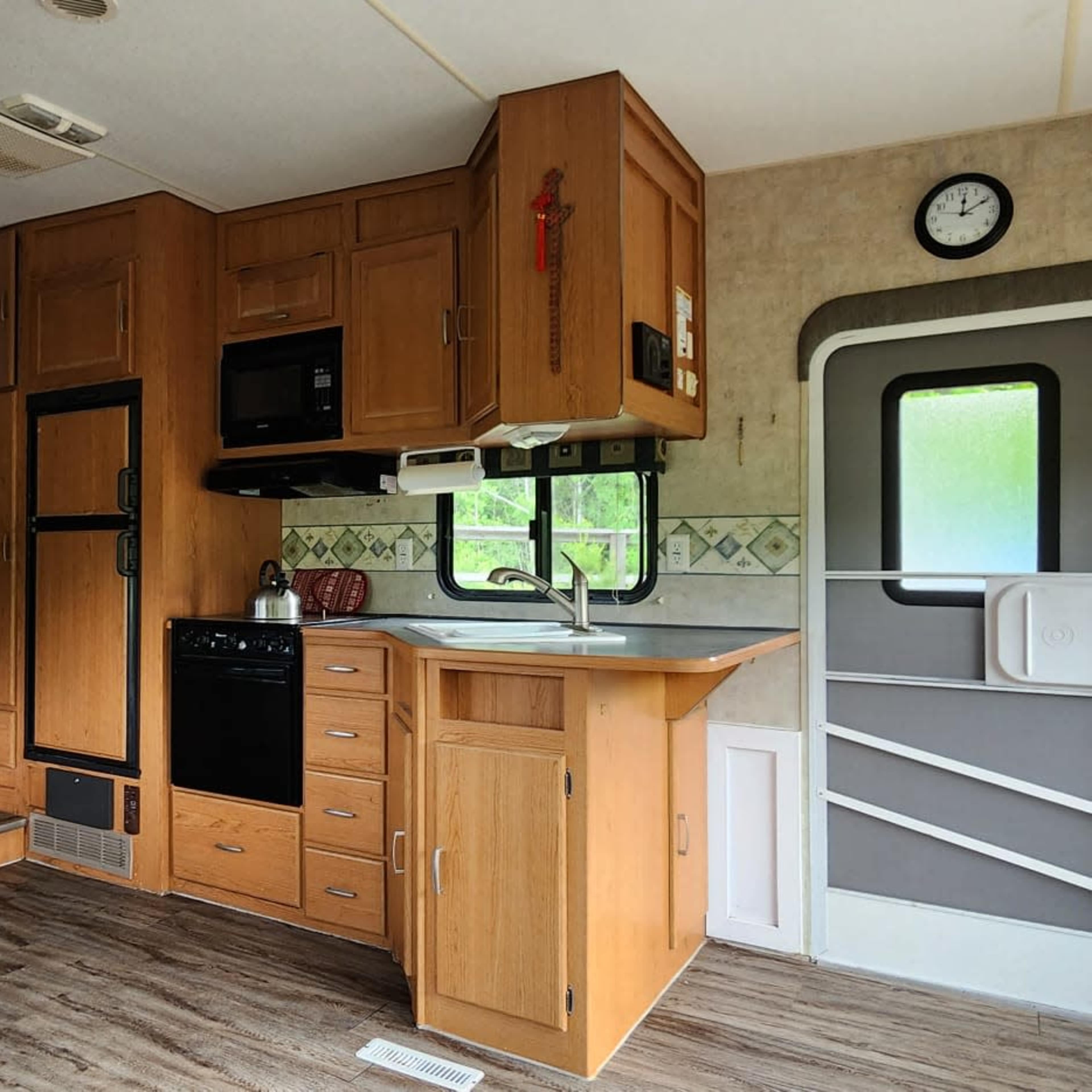 The interior of a camper with wooden cabinetry, a kitchen area, and a dining table.