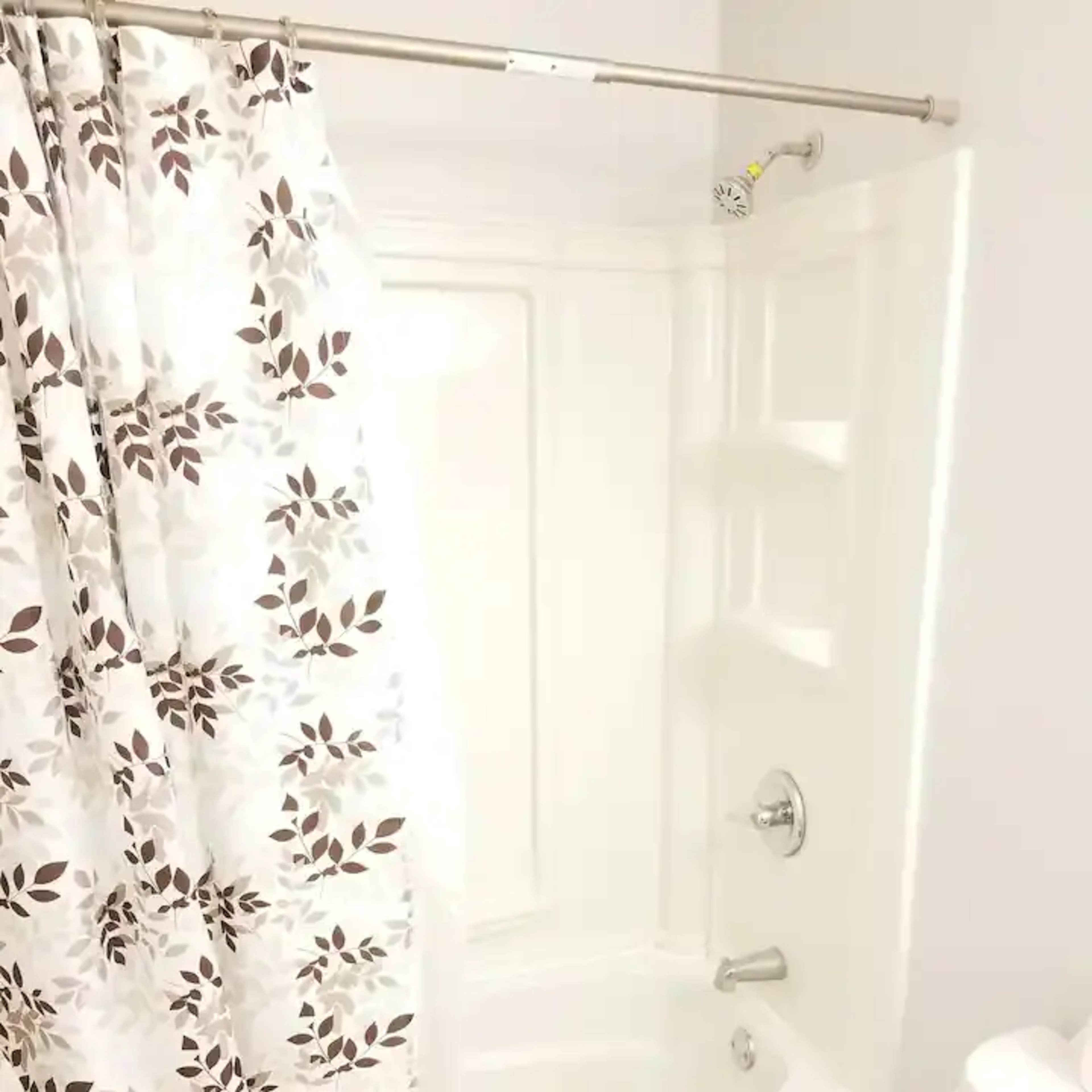 A bathroom with a bathtub, a shower curtain featuring a floral pattern, and a toilet nearby.