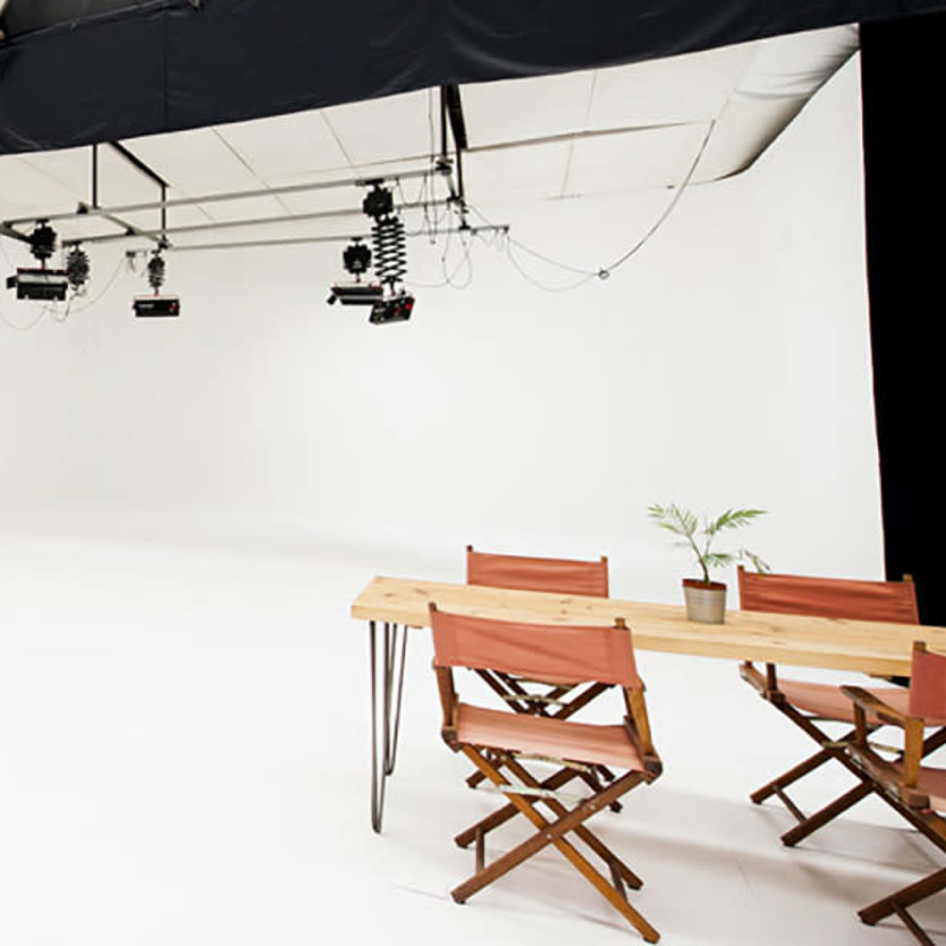 A spacious, minimally decorated studio with white walls, a clean floor, and a wooden table set with chairs.