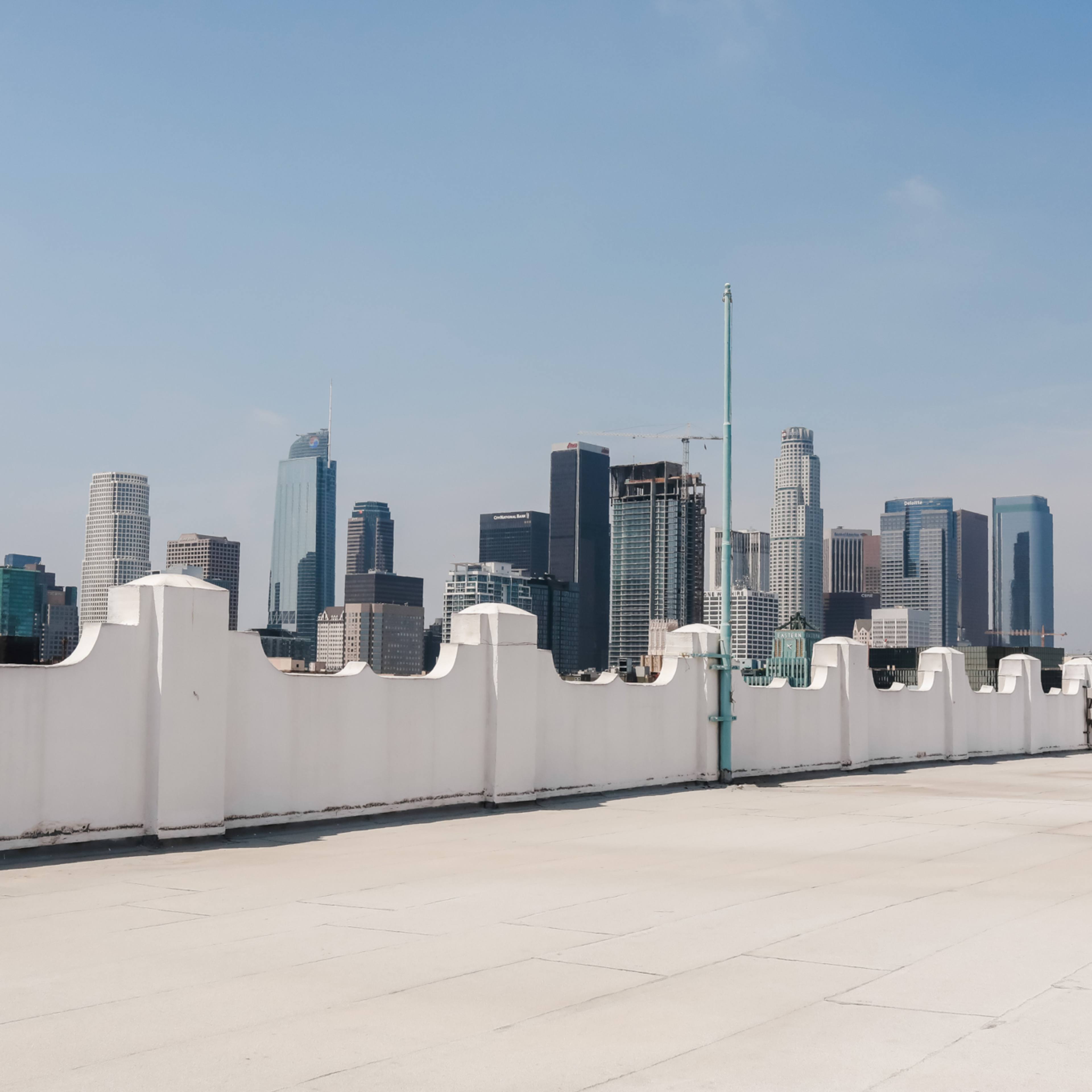 A rooftop view of a city skyline featuring tall buildings against a clear blue sky.