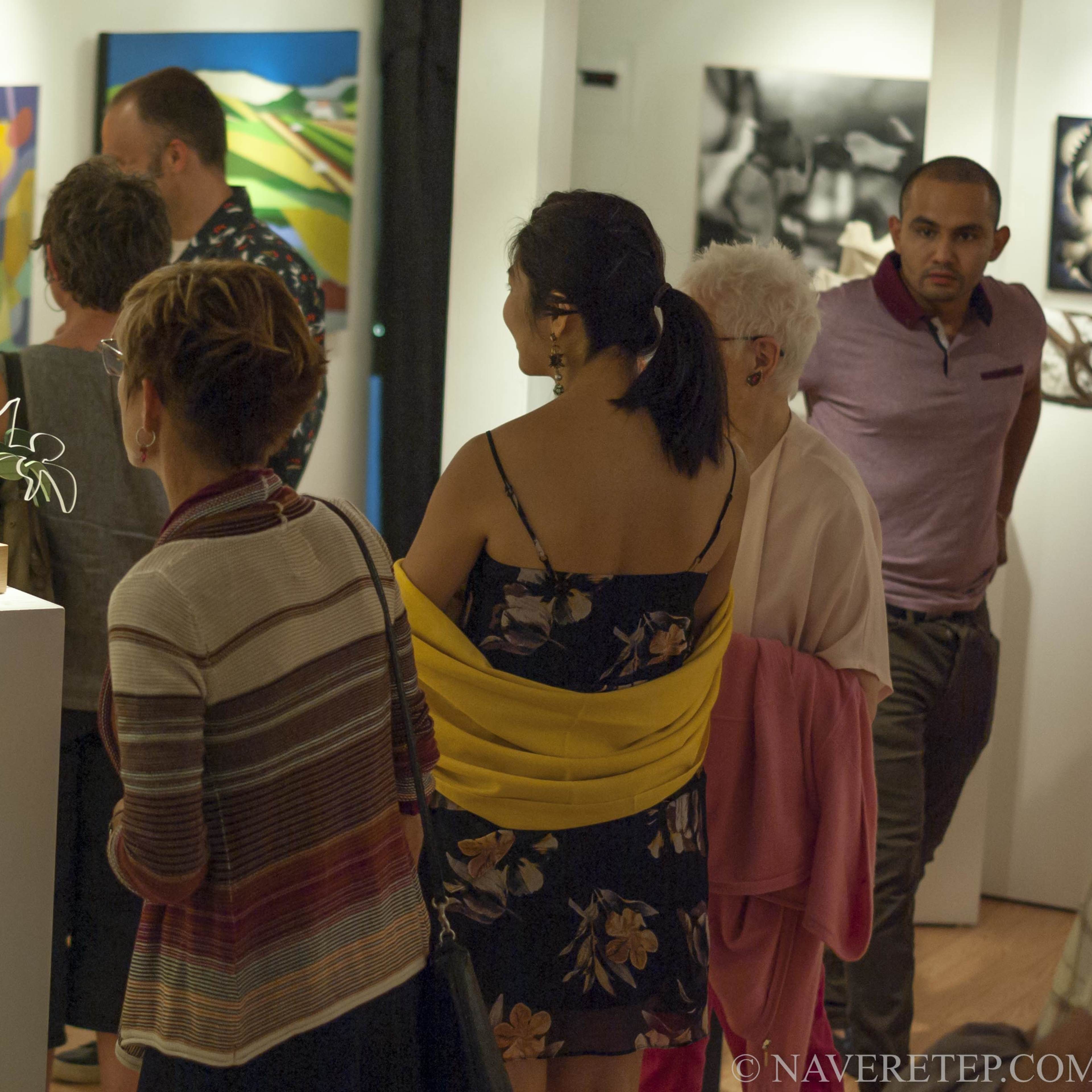 A group of people views artwork at an art gallery exhibition.