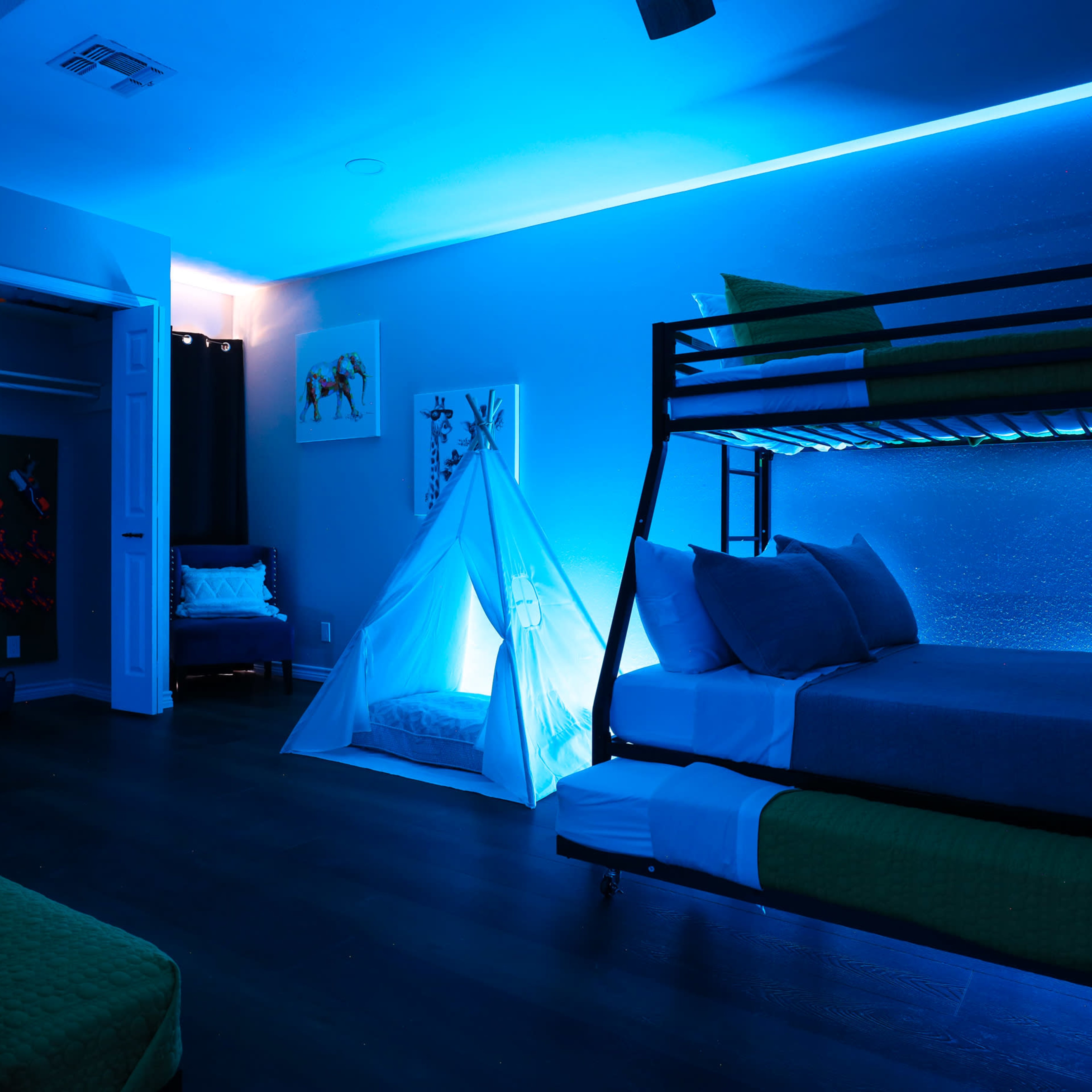 A dimly lit bedroom features bunk beds, a tent structure, and blue ambient lighting.