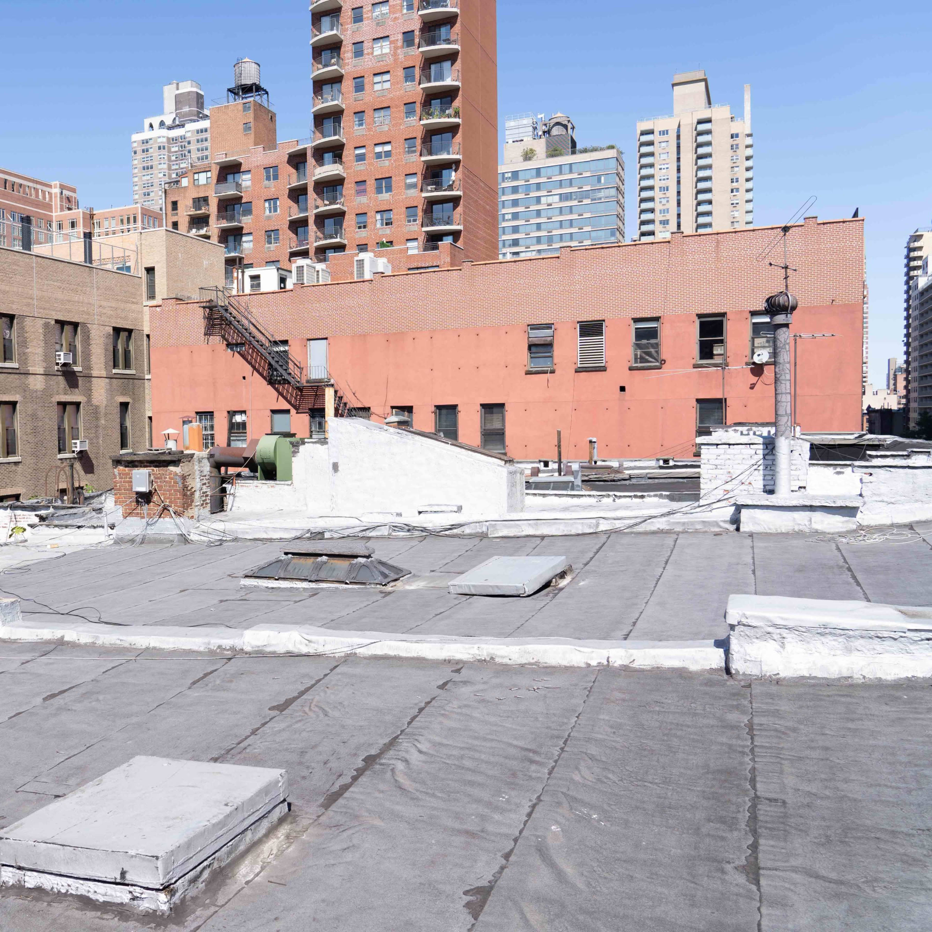 A view of urban rooftops with buildings in the background under a clear sky.