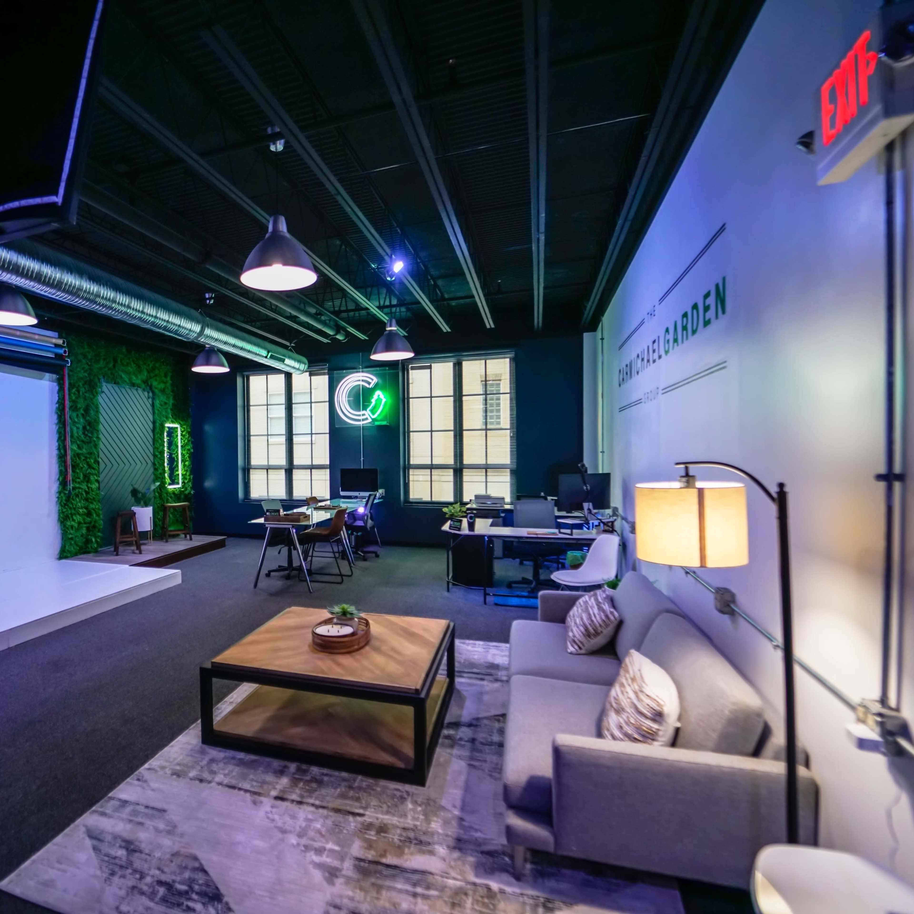 A modern studio space with a seating area, a green wall, and equipment for photography and production.