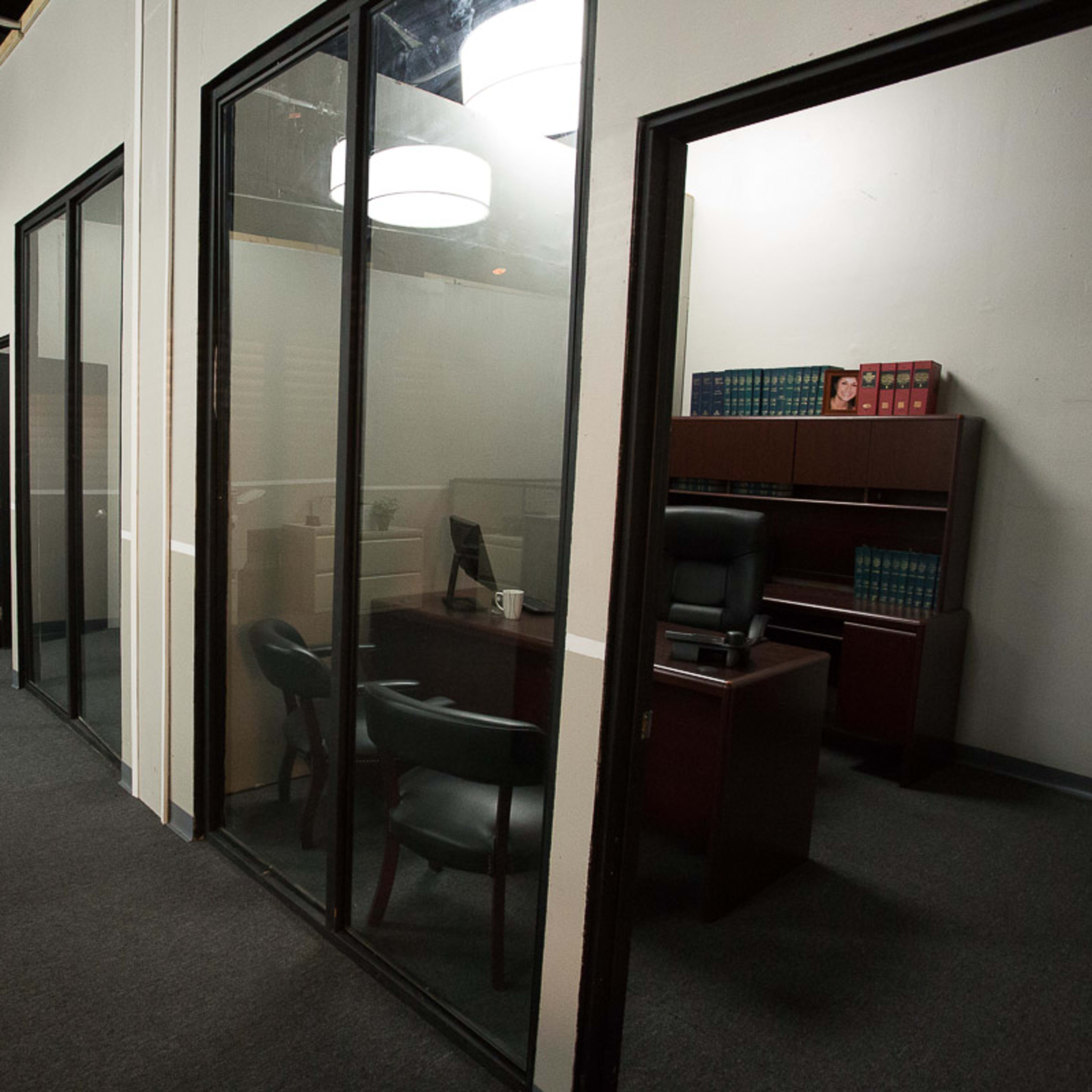 A modern office space with glass-walled meeting rooms and a desk set up in one of the enclosed areas.