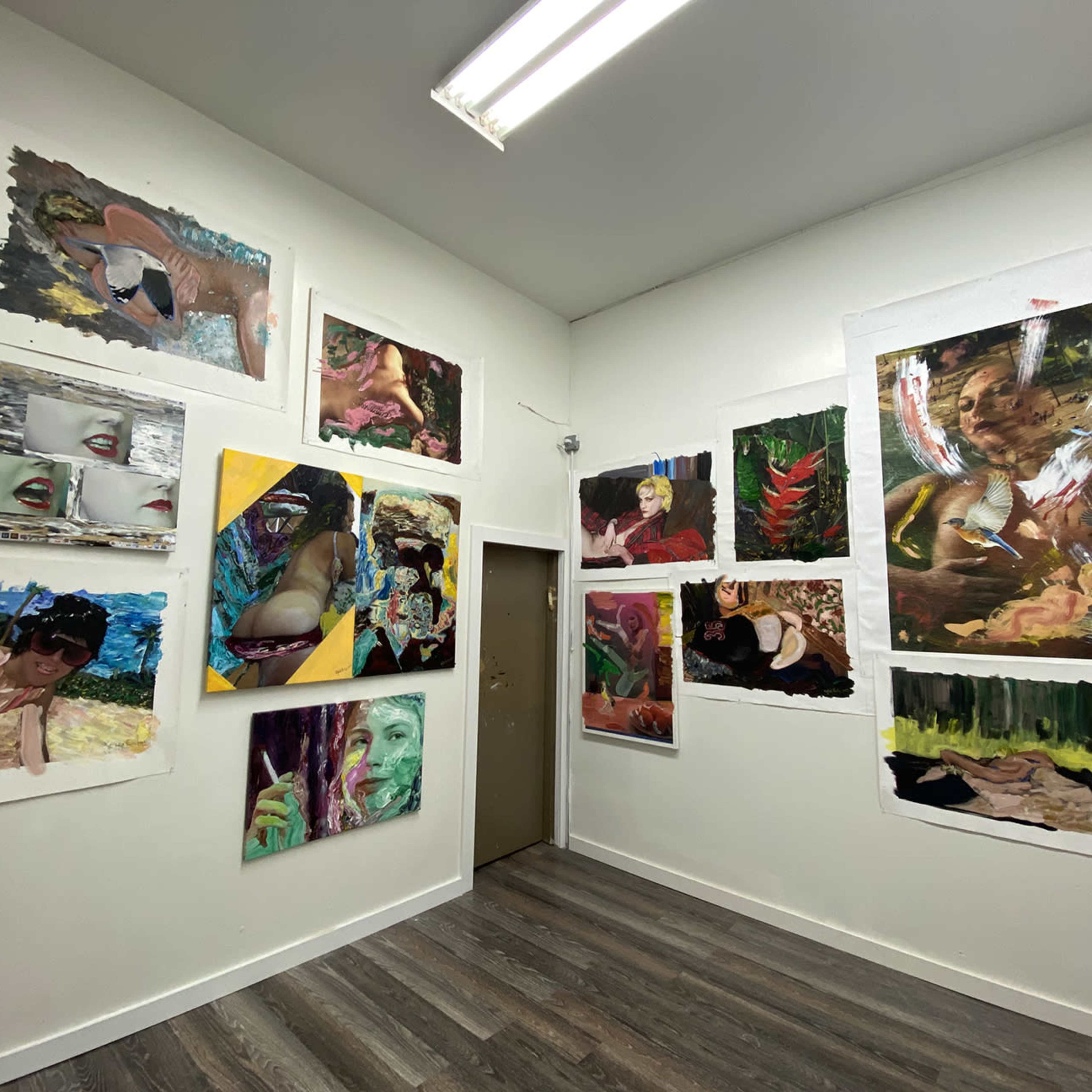A gallery-like room with colorful paintings and artworks displayed on the walls, featuring a variety of styles and subjects.