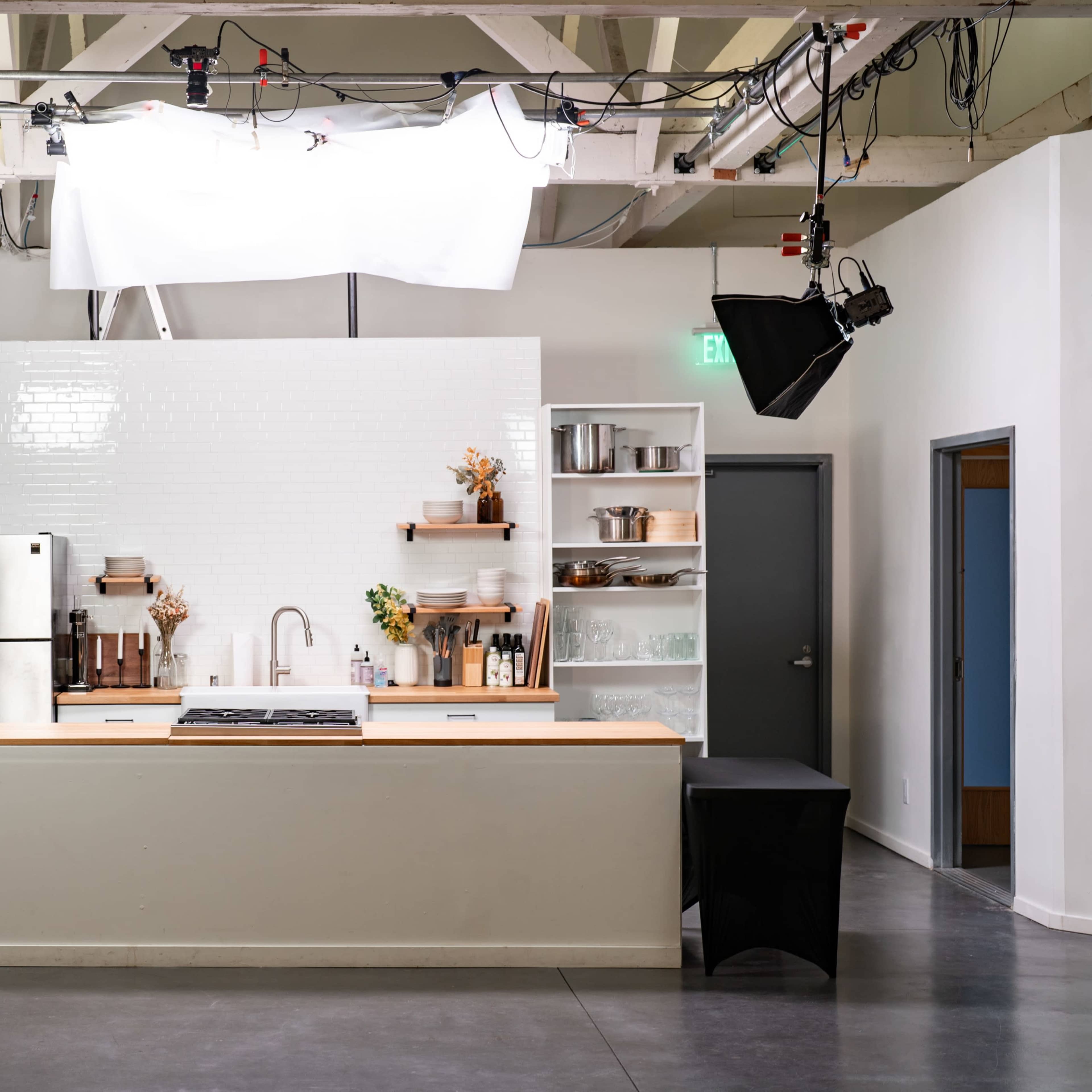 A modern kitchen setup with a central island, stainless steel refrigerator, and various cooking utensils arranged on shelves.