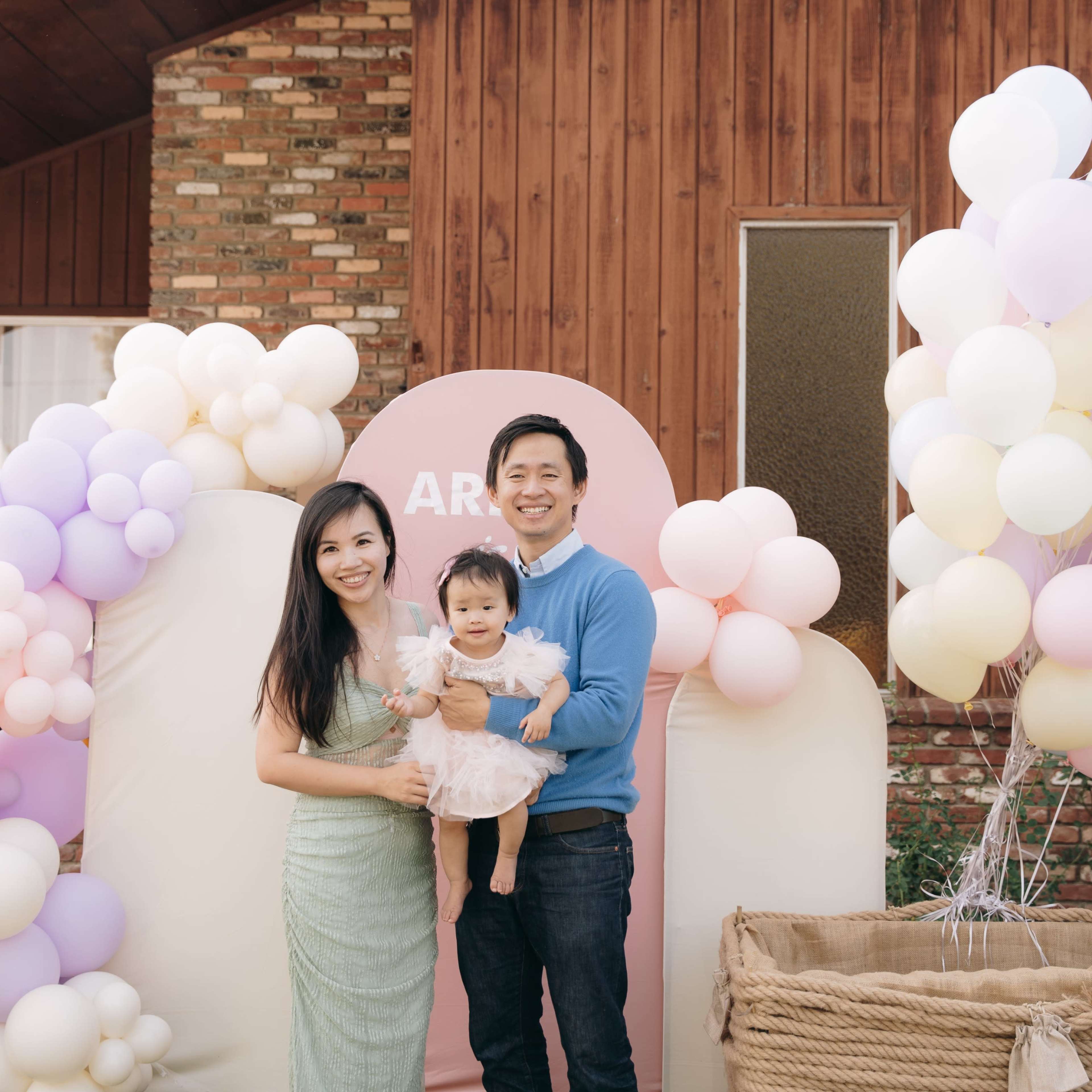 A family poses together in front of a balloon arch at a celebration event.