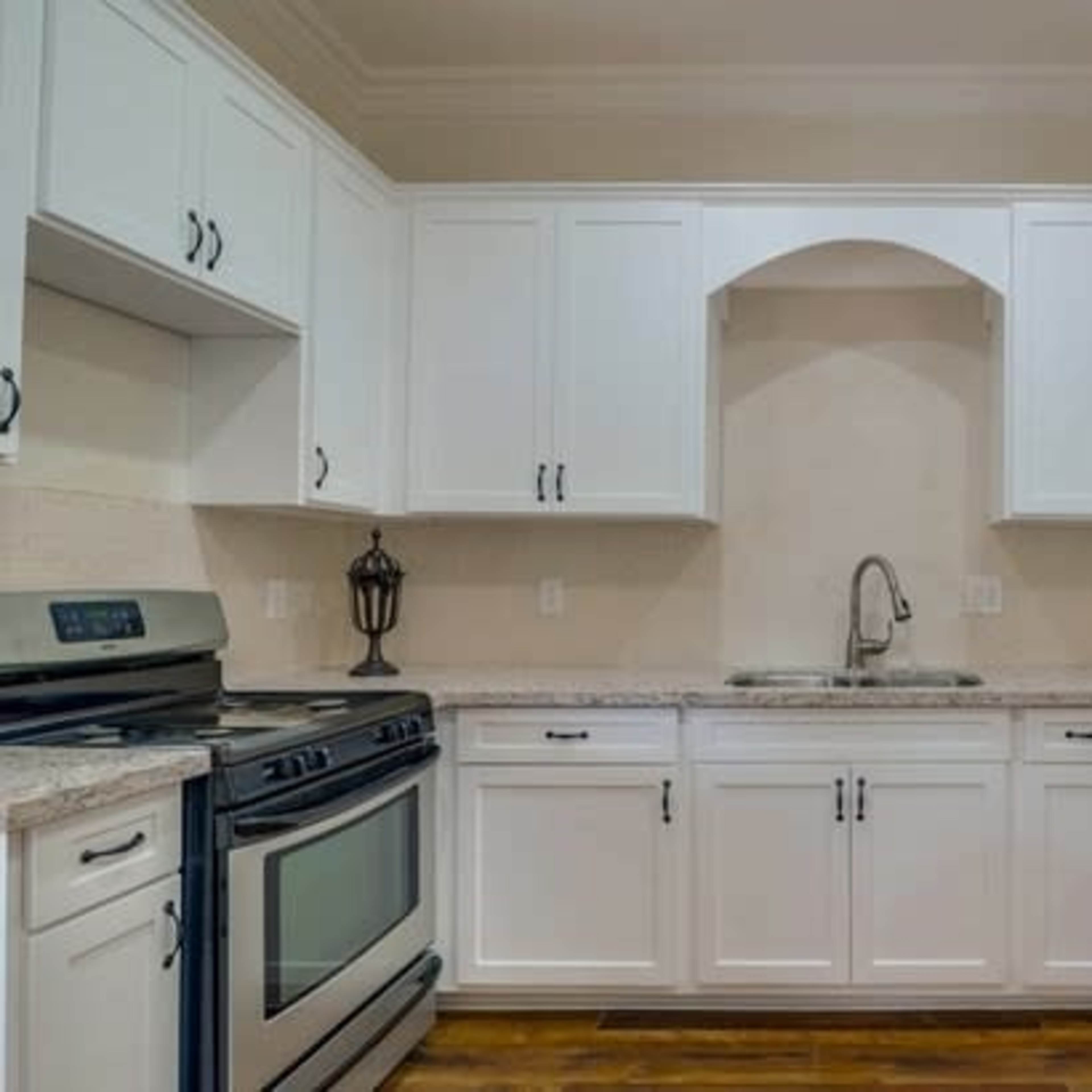A modern kitchen with white cabinets, a stainless steel stove, and a granite countertop.