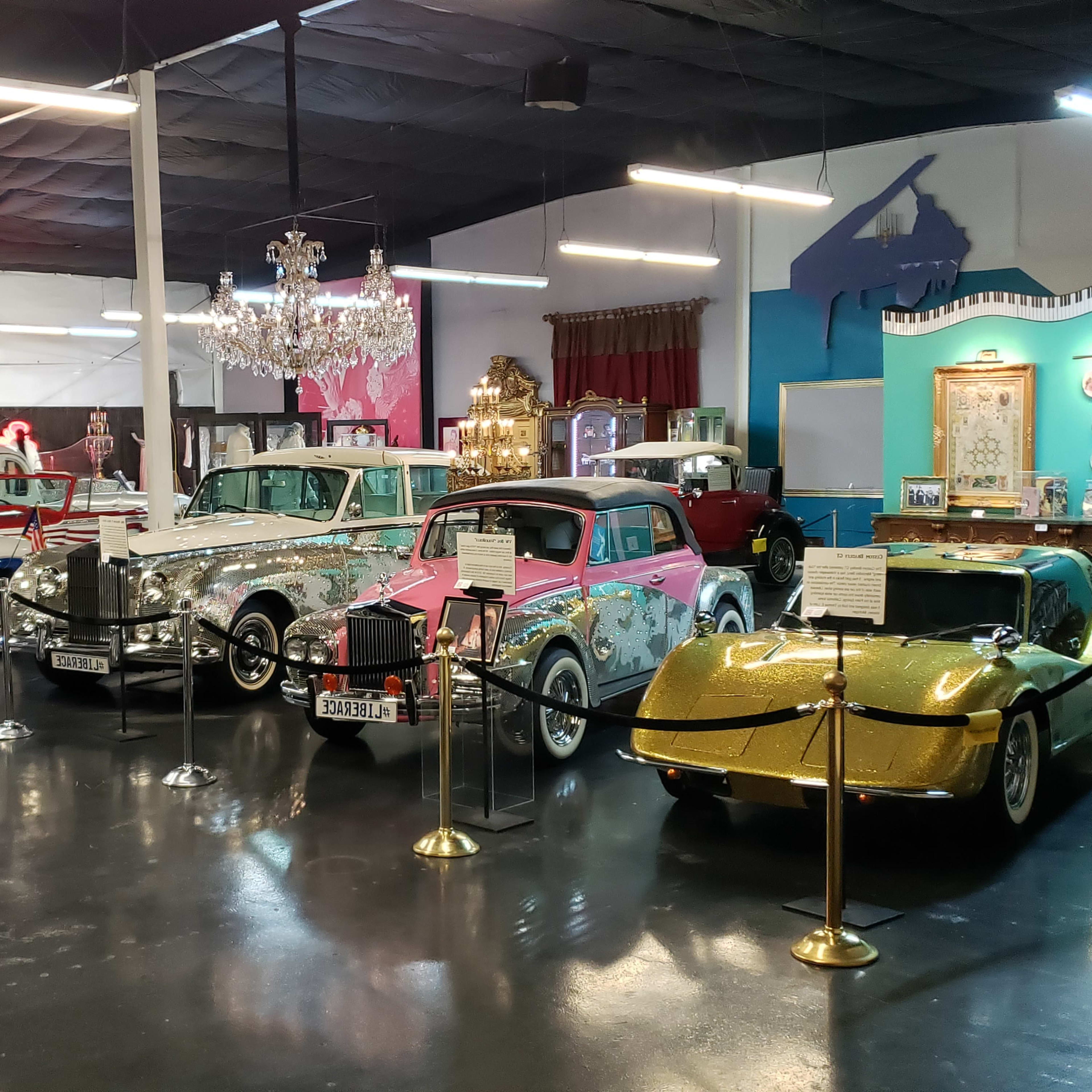 A collection of vintage cars displayed in a museum-like setting, featuring various models and styles under bright lighting.