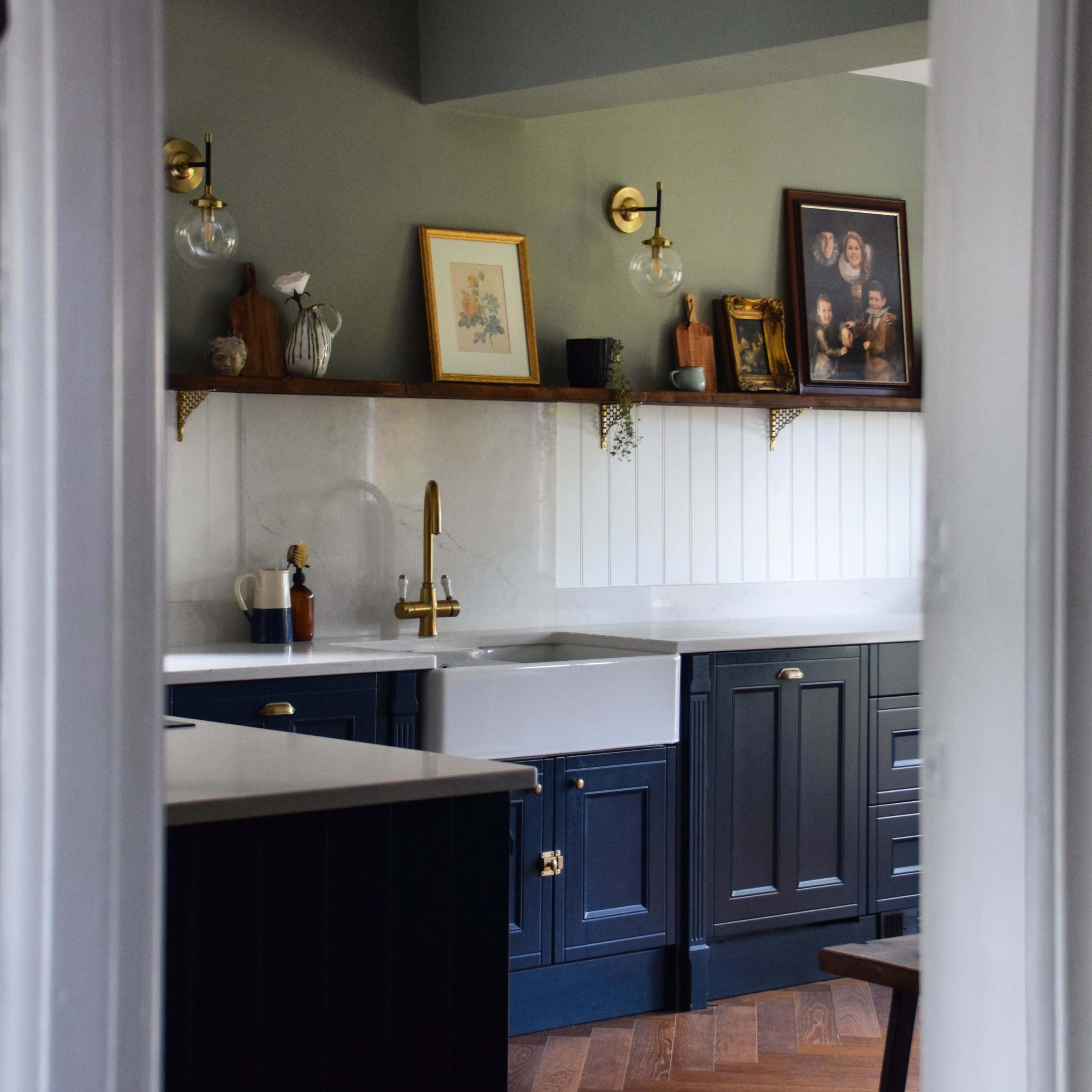 A modern kitchen with dark wooden cabinets, a white sink, and framed artwork on the walls.