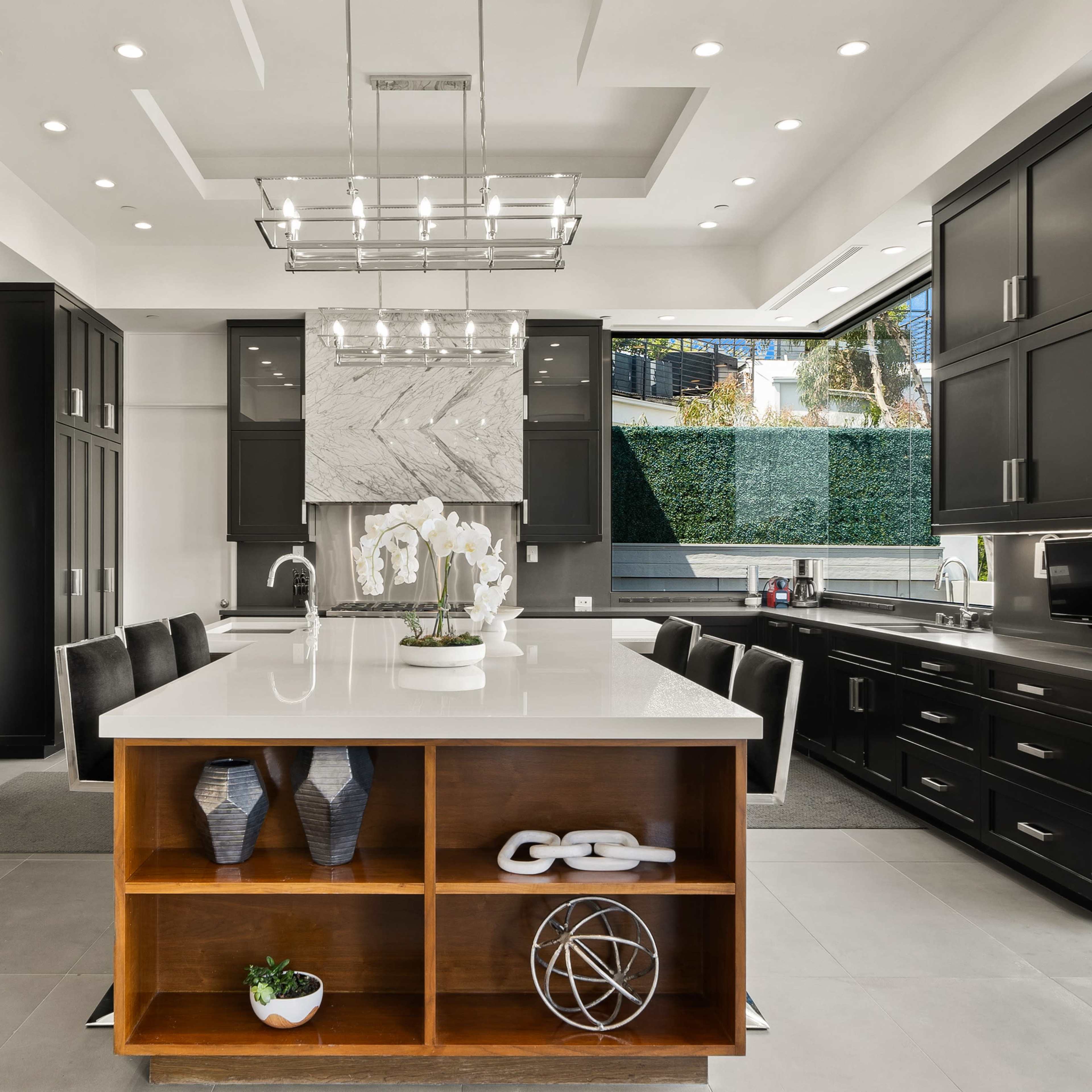 A modern kitchen features dark cabinetry, a central island with a white countertop, and a stylish pendant light above.