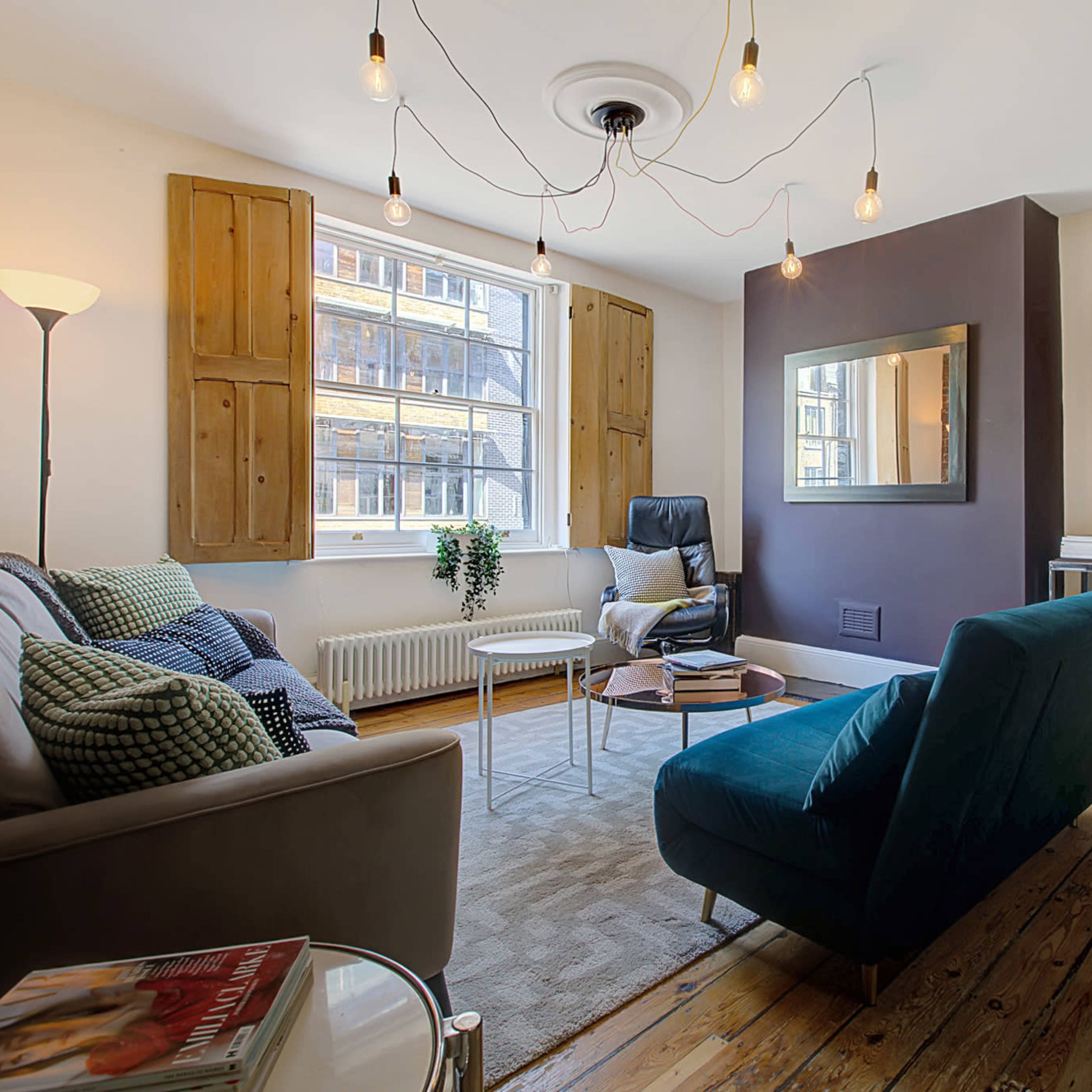A stylish living room with a sofa, a teal chair, a small coffee table, and a framed artwork featuring a red star on one wall.
