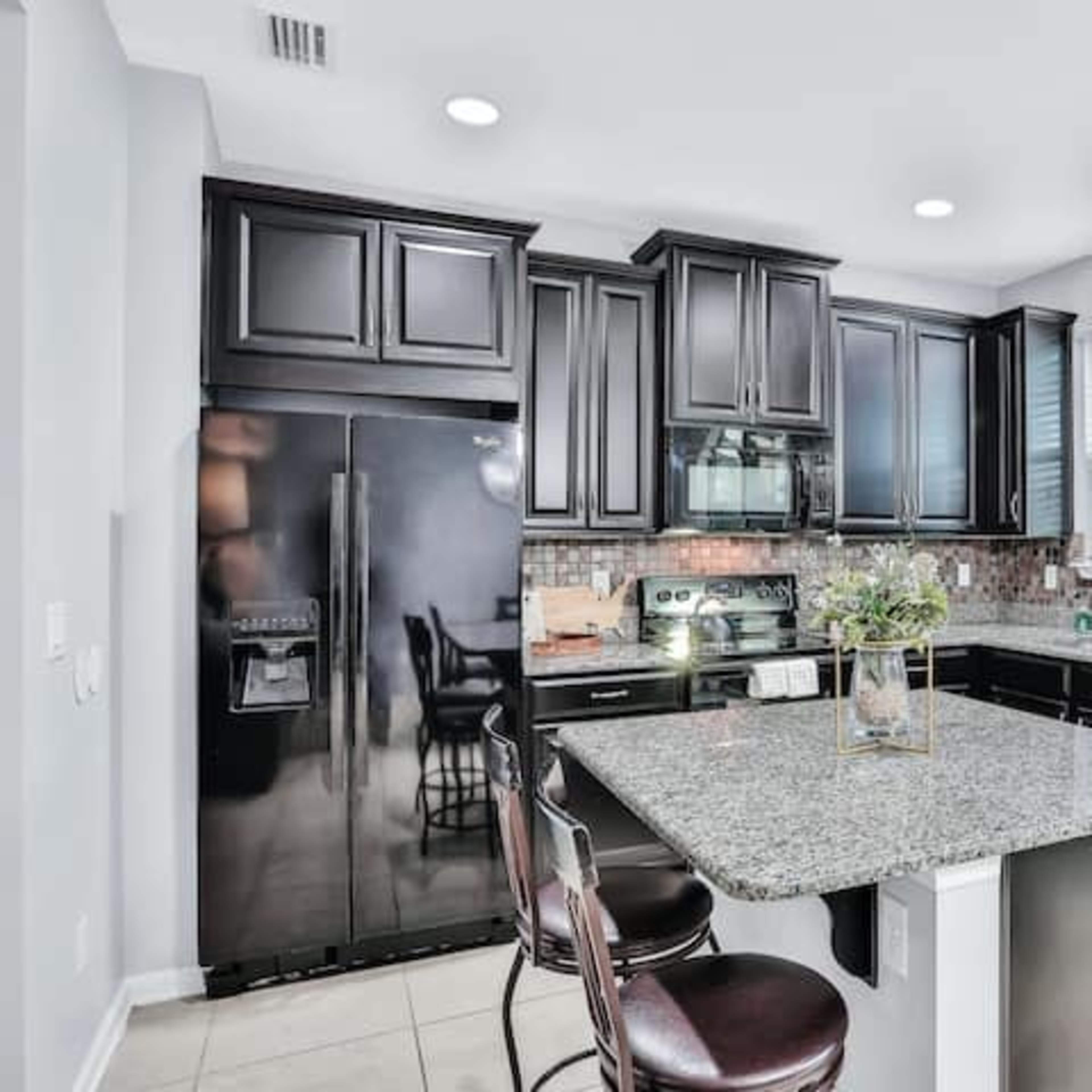 The kitchen features dark wooden cabinets, a granite countertop island, and modern appliances.
