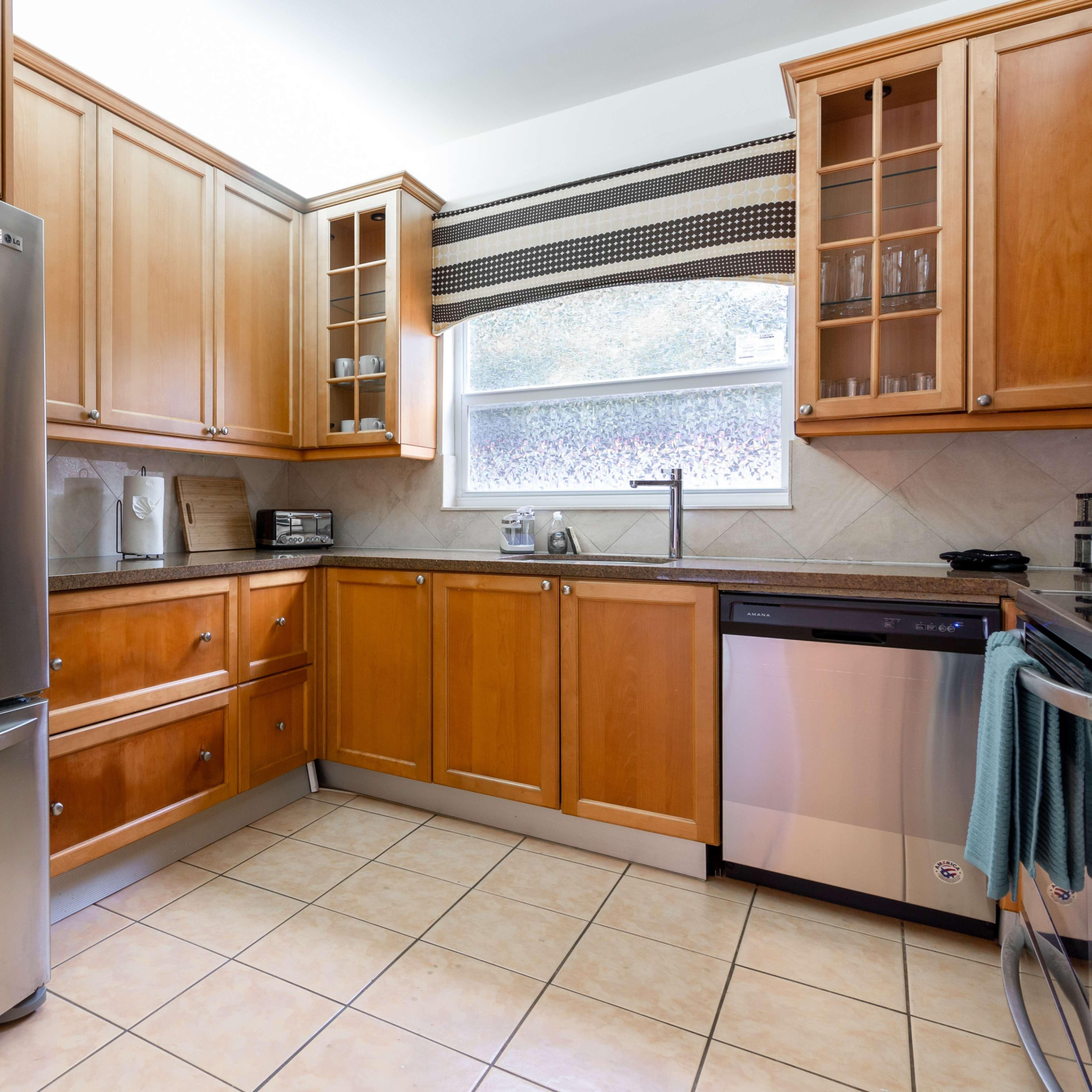 A kitchen with wooden cabinets, stainless steel appliances, and tiled flooring.