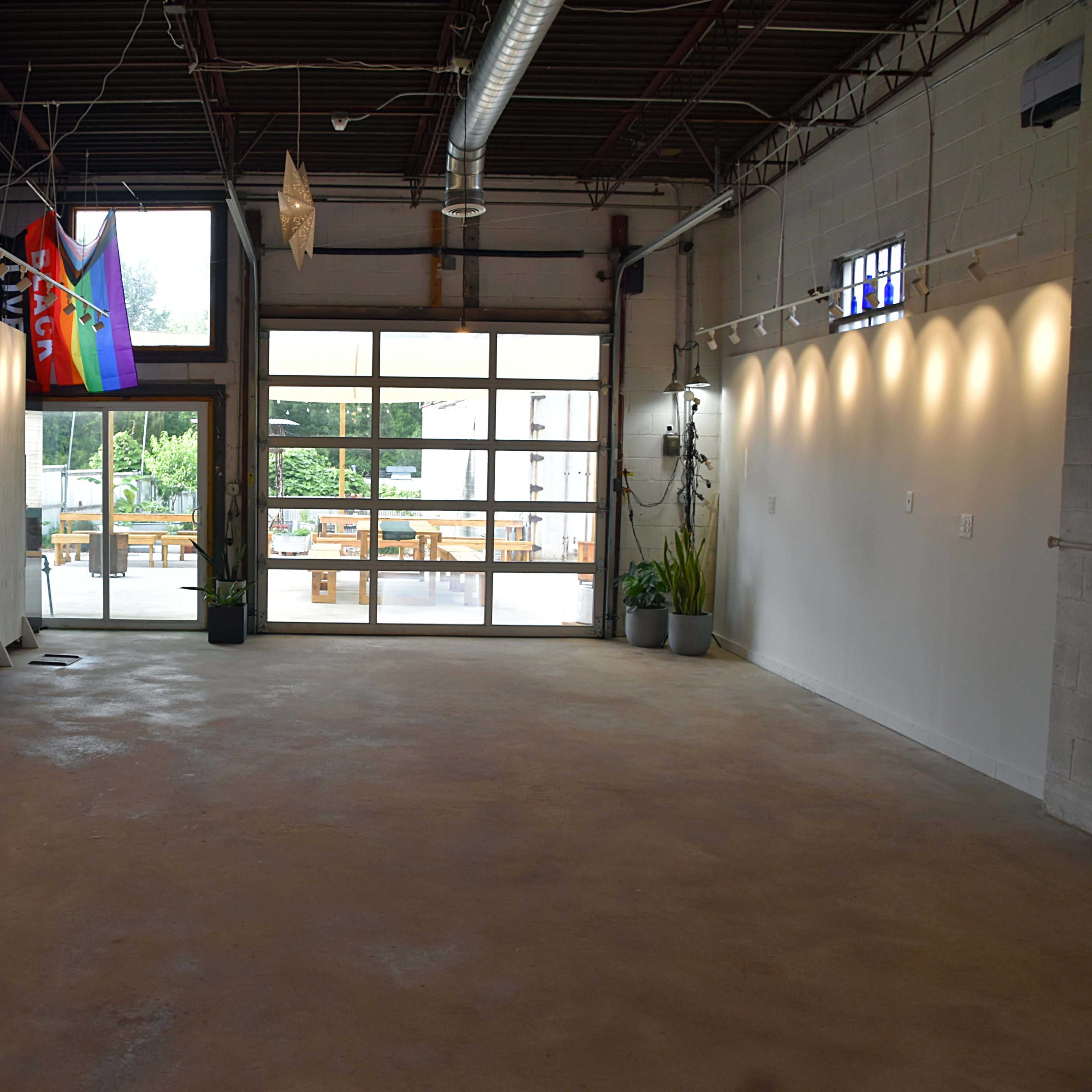 An empty interior space with white walls, large windows, and a patio area visible outside.